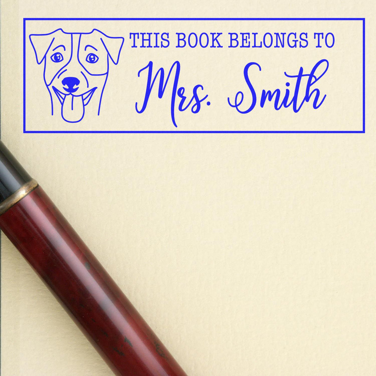 Blue book stamp seal with dog outline and Mrs. Smith text in a bordered rectangle on cream paper, beside a brown stamp handle.