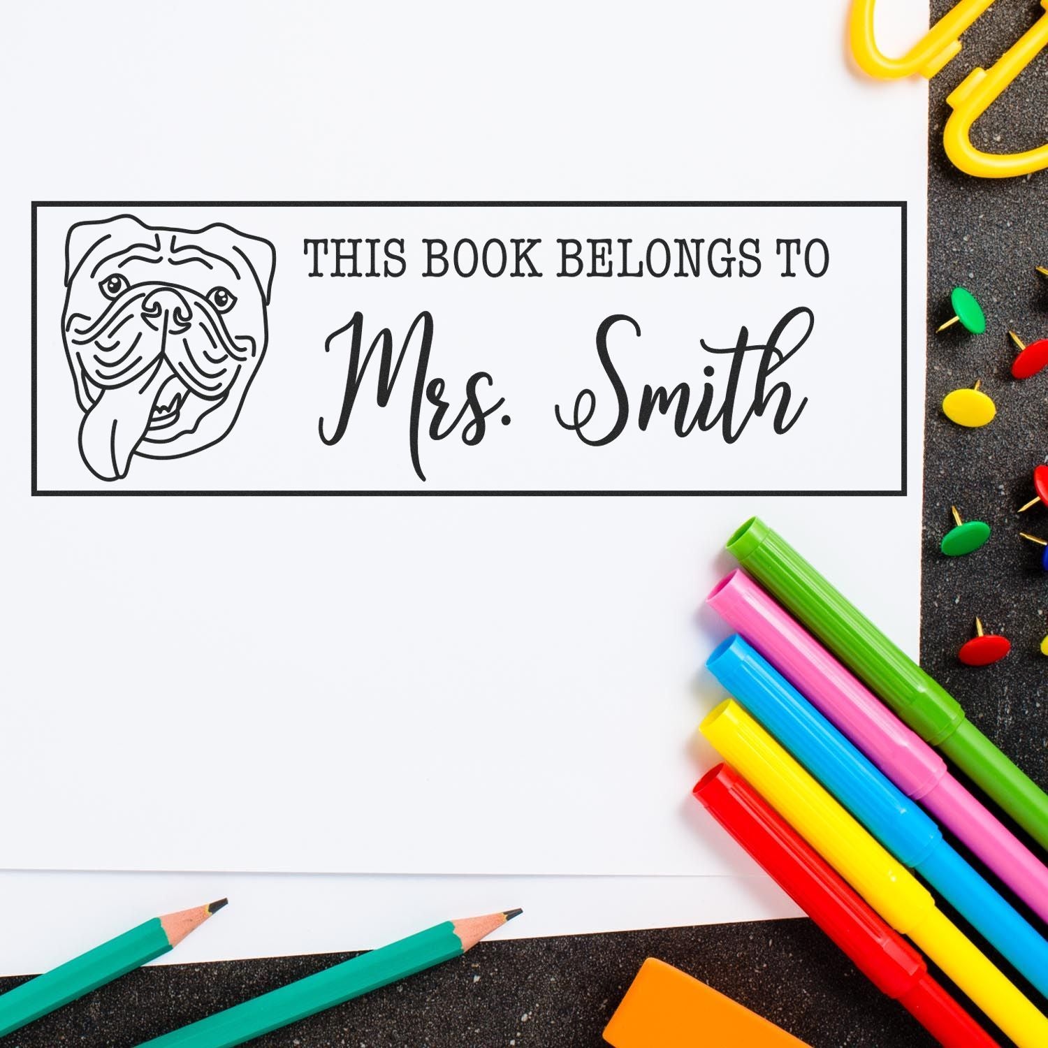 Personalized book stamp and seal with bulldog, black text on white label, surrounded by colorful school supplies.