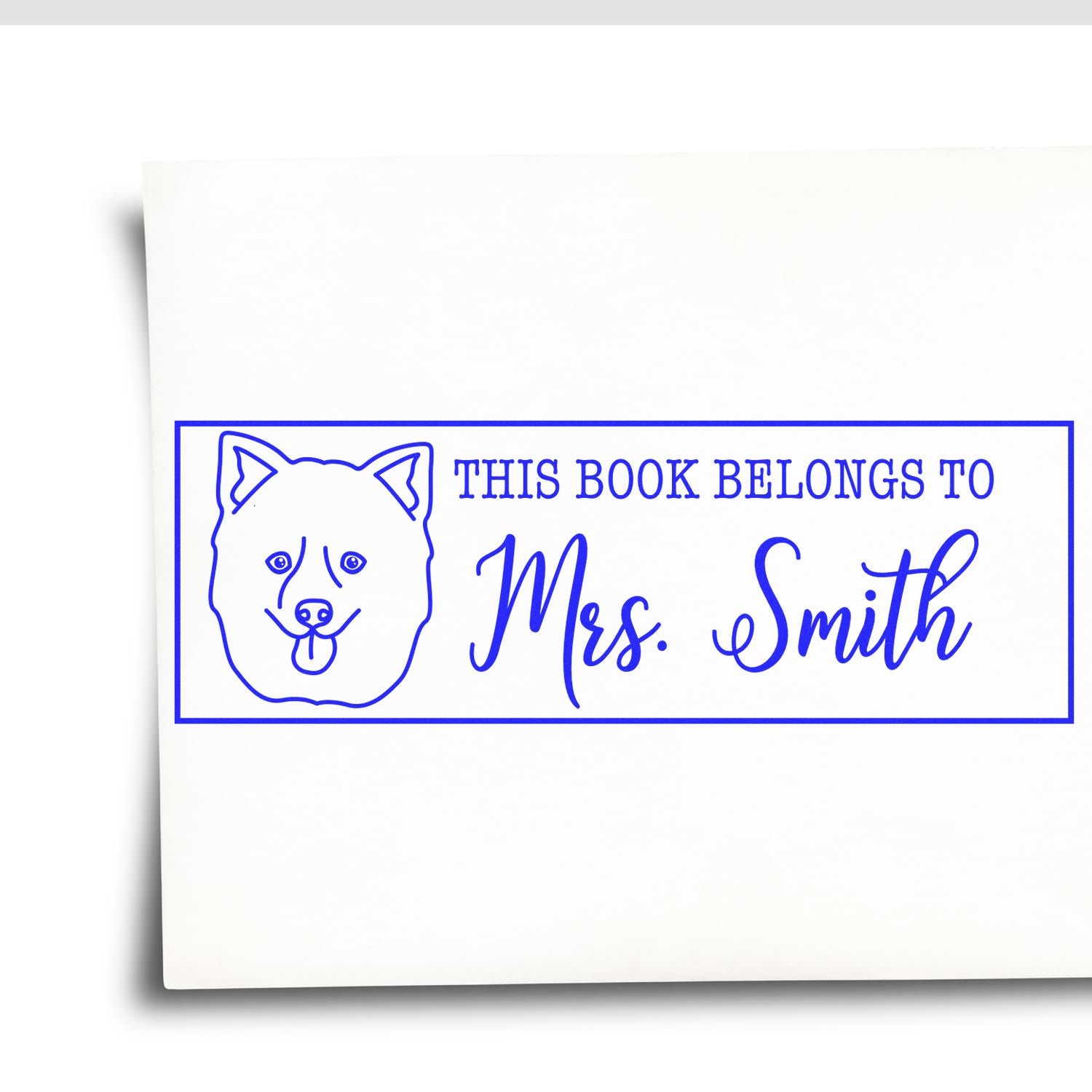Blue custom self-inking book stamp with dog outline and This Book Belongs to Mrs. Smith on white background.