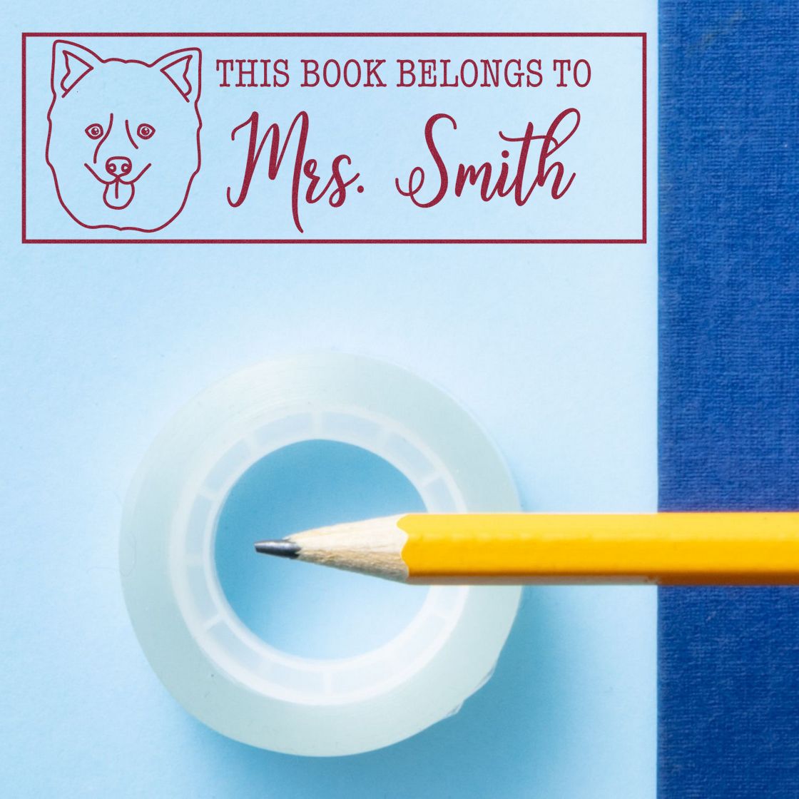 Red book stamp reading This Book Belongs to Mrs. Smith with dog icon, plus clear seal and yellow pencil on blue background.