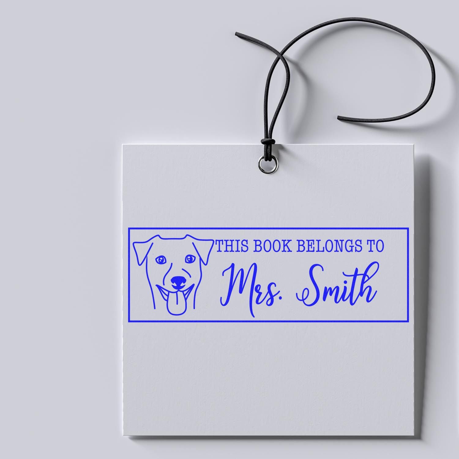 Blue personalized book stamp seal with dog icon and This book belongs to Mrs. Smith on white tag, black cord.
