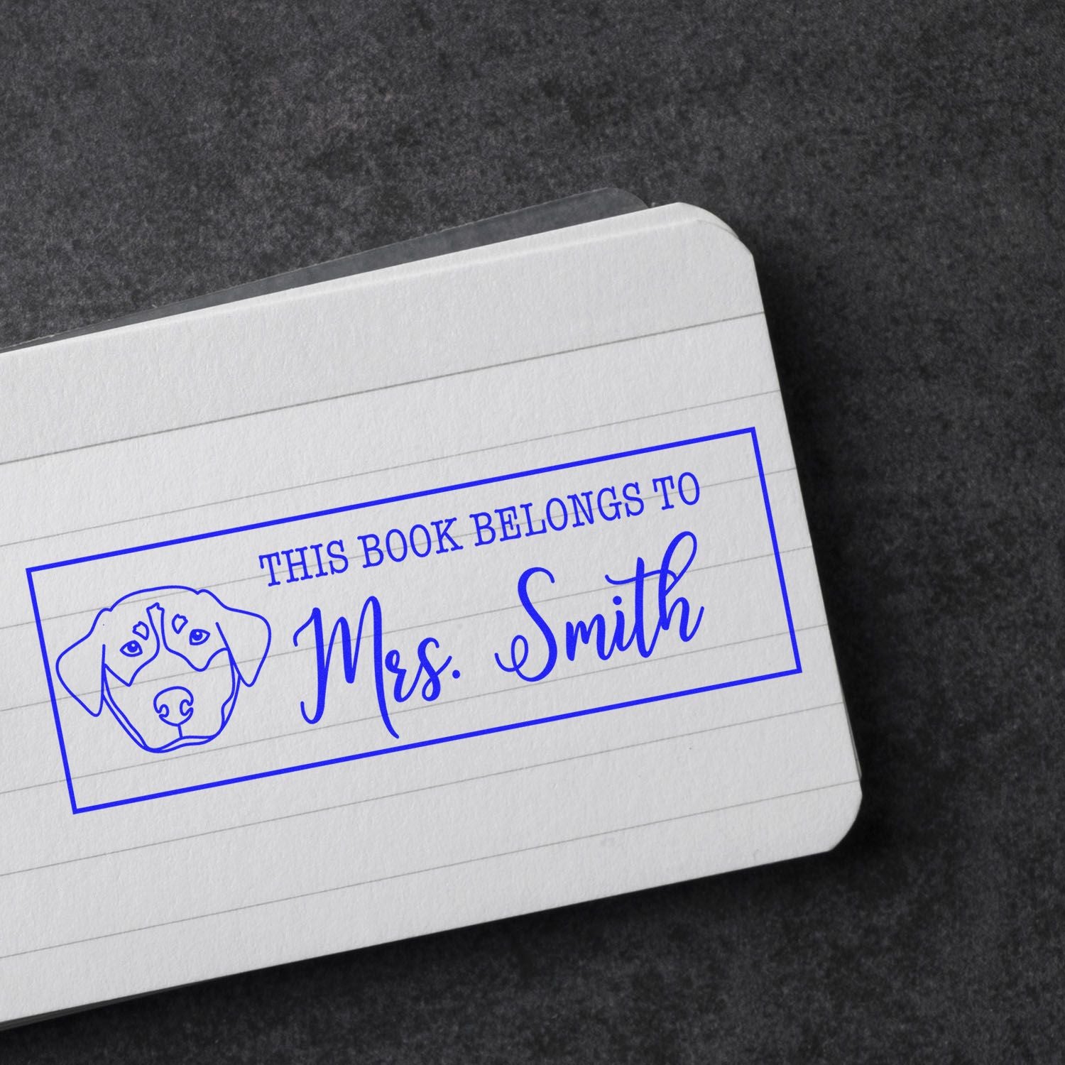 Blue custom bookplate stamp with dog seal and Mrs. Smith text on white lined paper.