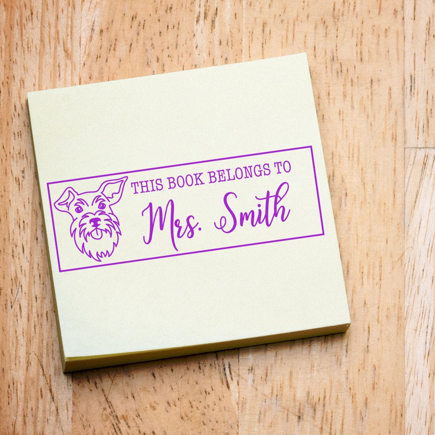 Cream custom book stamp and seal with purple dog and This Book Belongs to Mrs. Smith on wood.