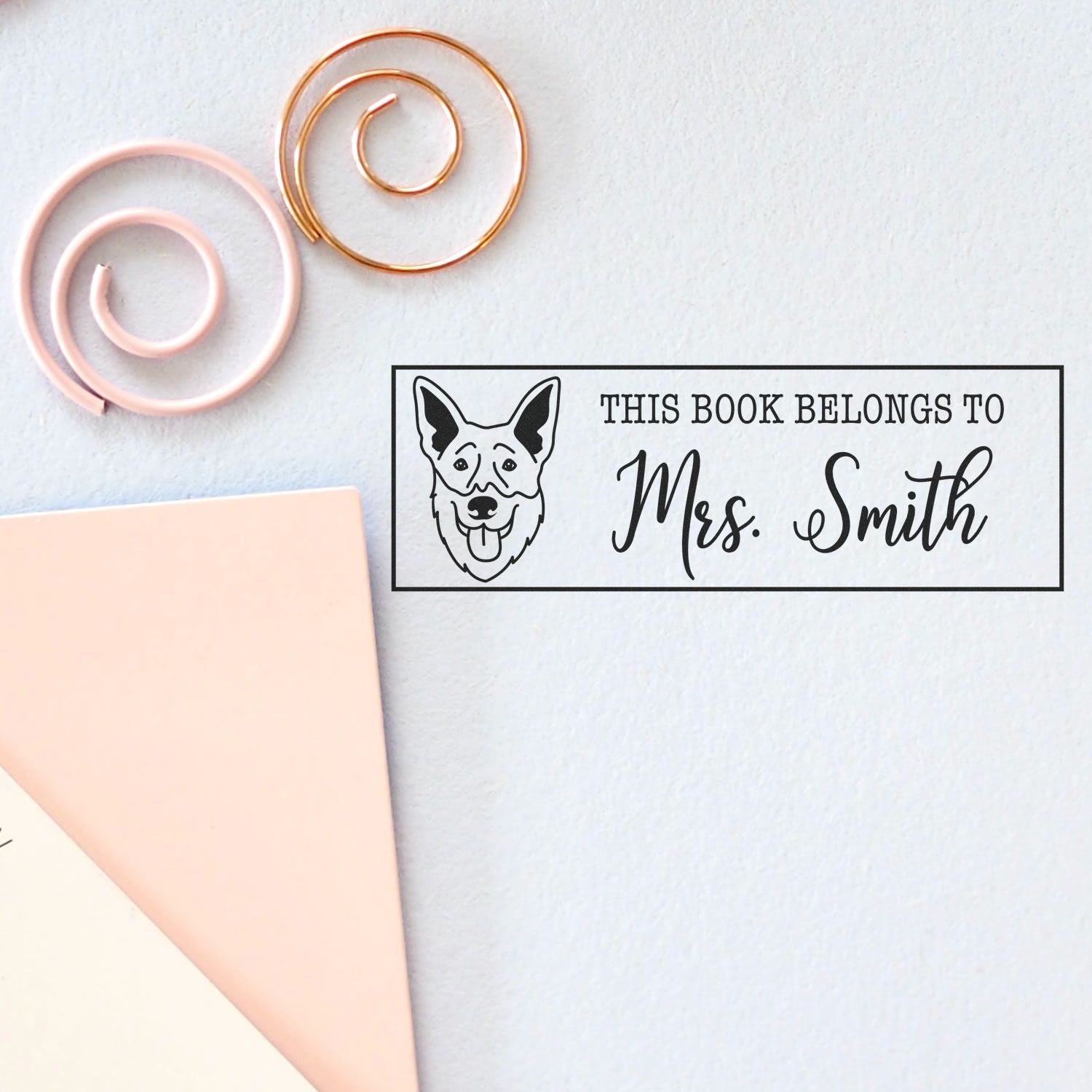 Custom black book stamp with dog seal and Mrs. Smith, beside pink and gold spiral wax seals on white paper.
