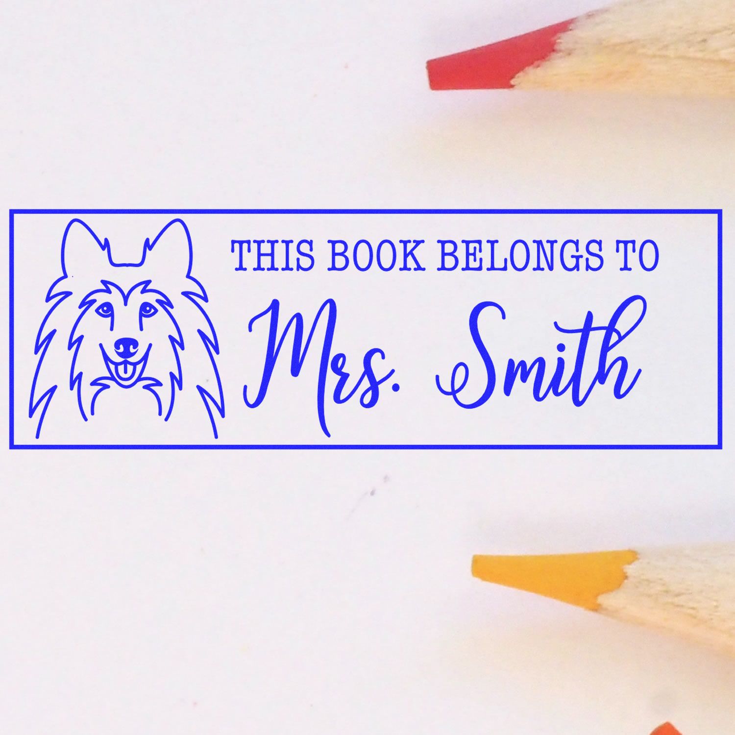 Blue personalized book stamp with dog outline, reading This Book Belongs to Mrs. Smith, on white paper.