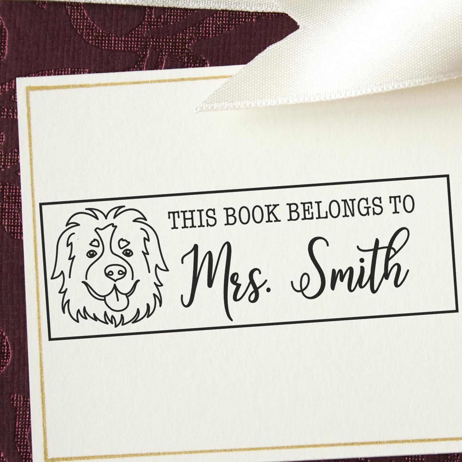 Custom bookplate stamp with dog seal design, black Mrs. Smith text, white card with gold border on burgundy background