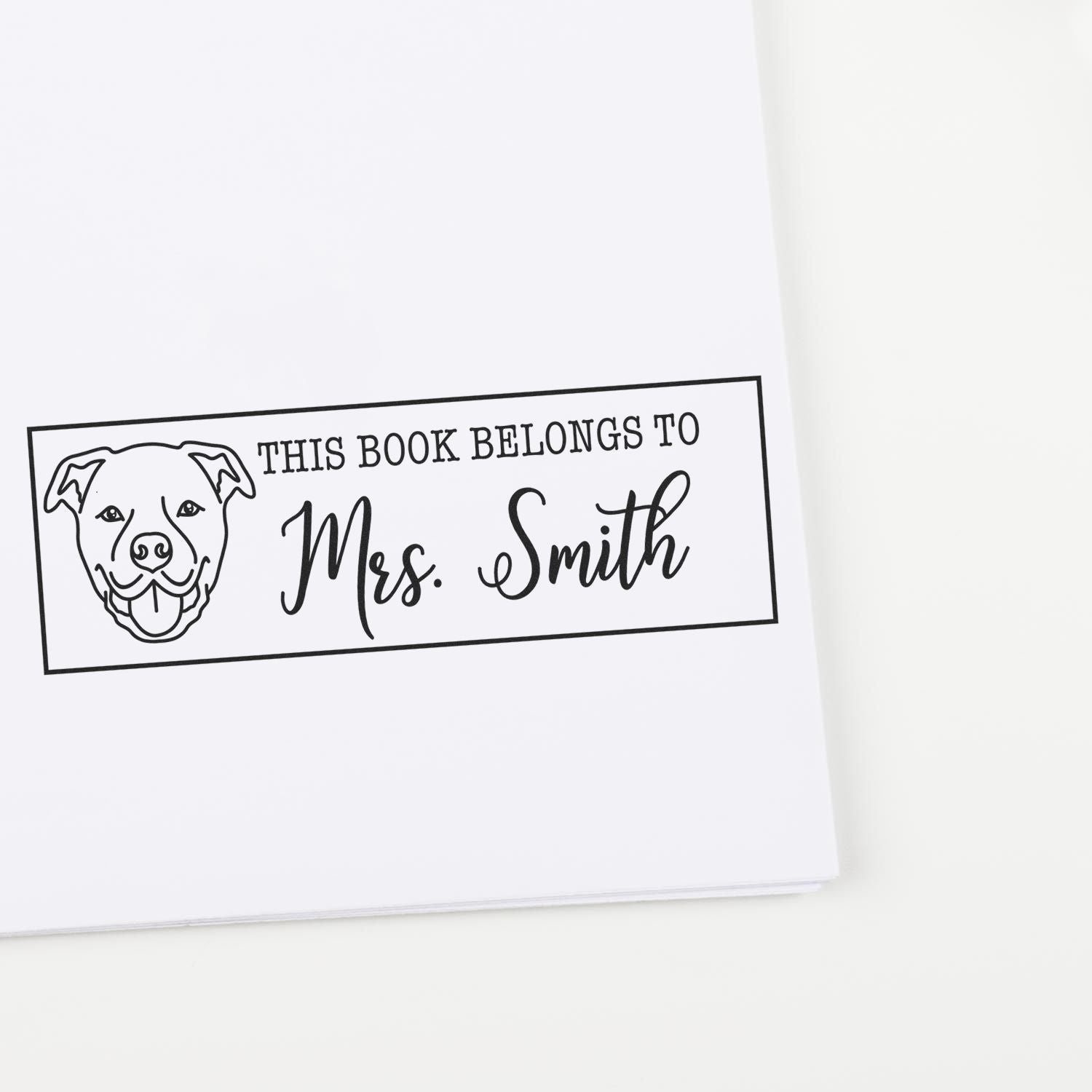 Black personalized book stamp and seal with dog outline, reading This Book Belongs to Mrs. Smith on white background.