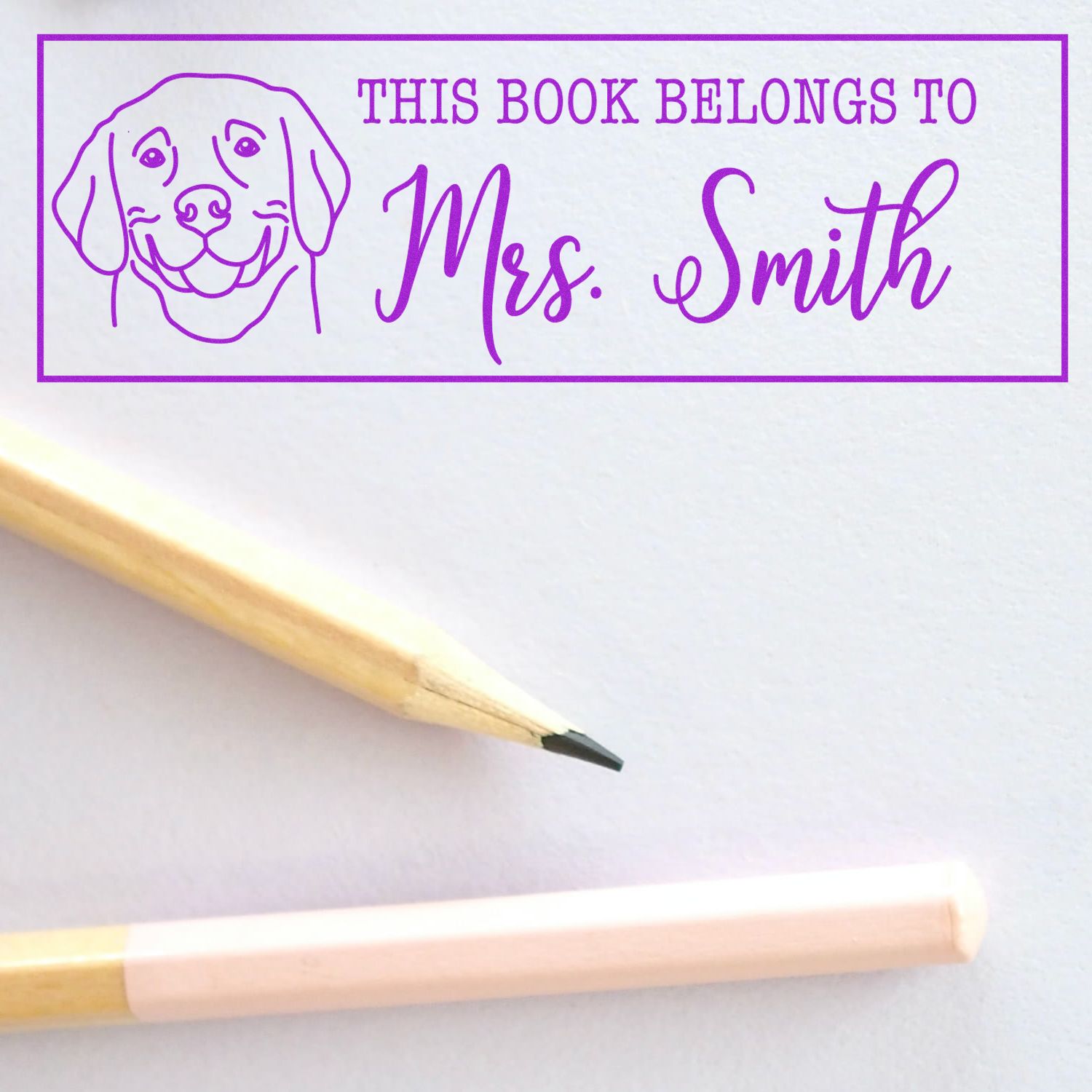 Purple personalized book stamp and seal with dog icon, This book belongs to Mrs. Smith, shown beside a pencil.