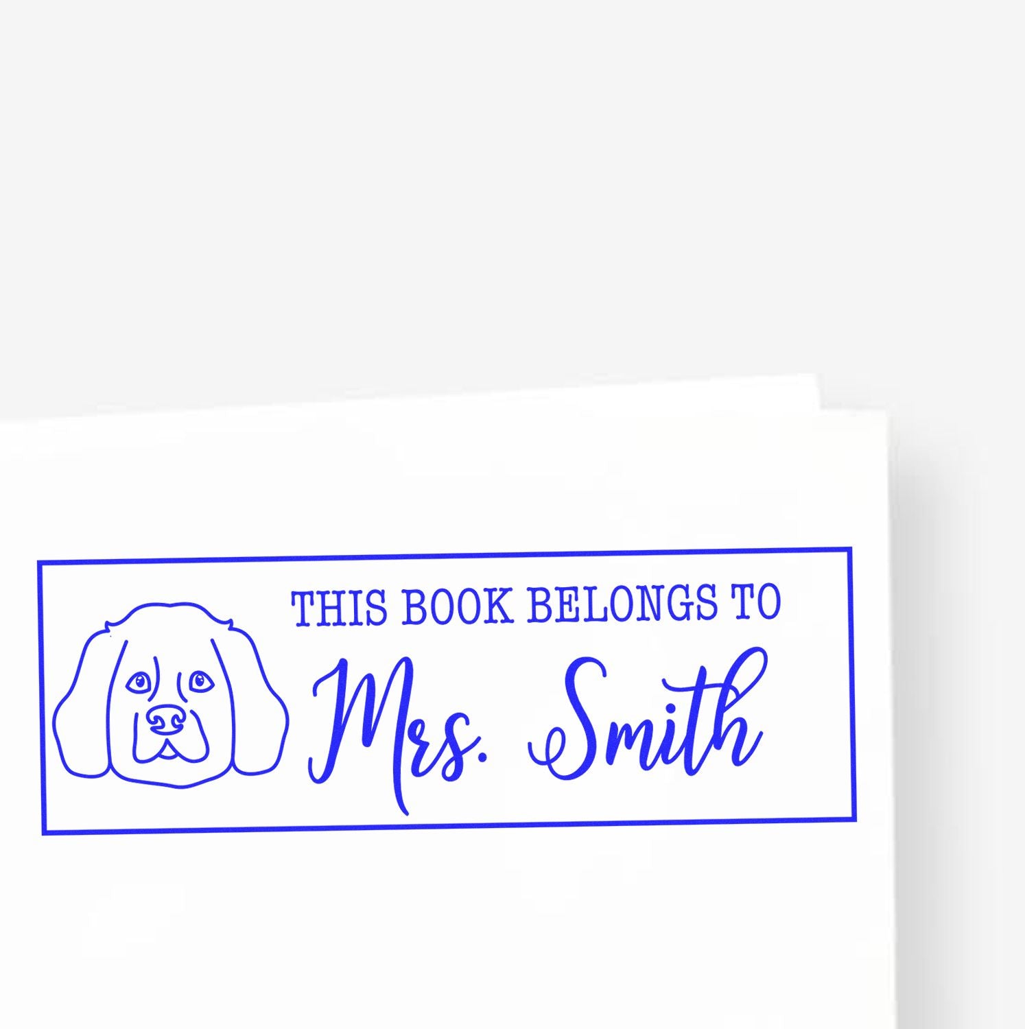 Blue custom book stamp with dog outline and This book belongs to Mrs. Smith on white background.