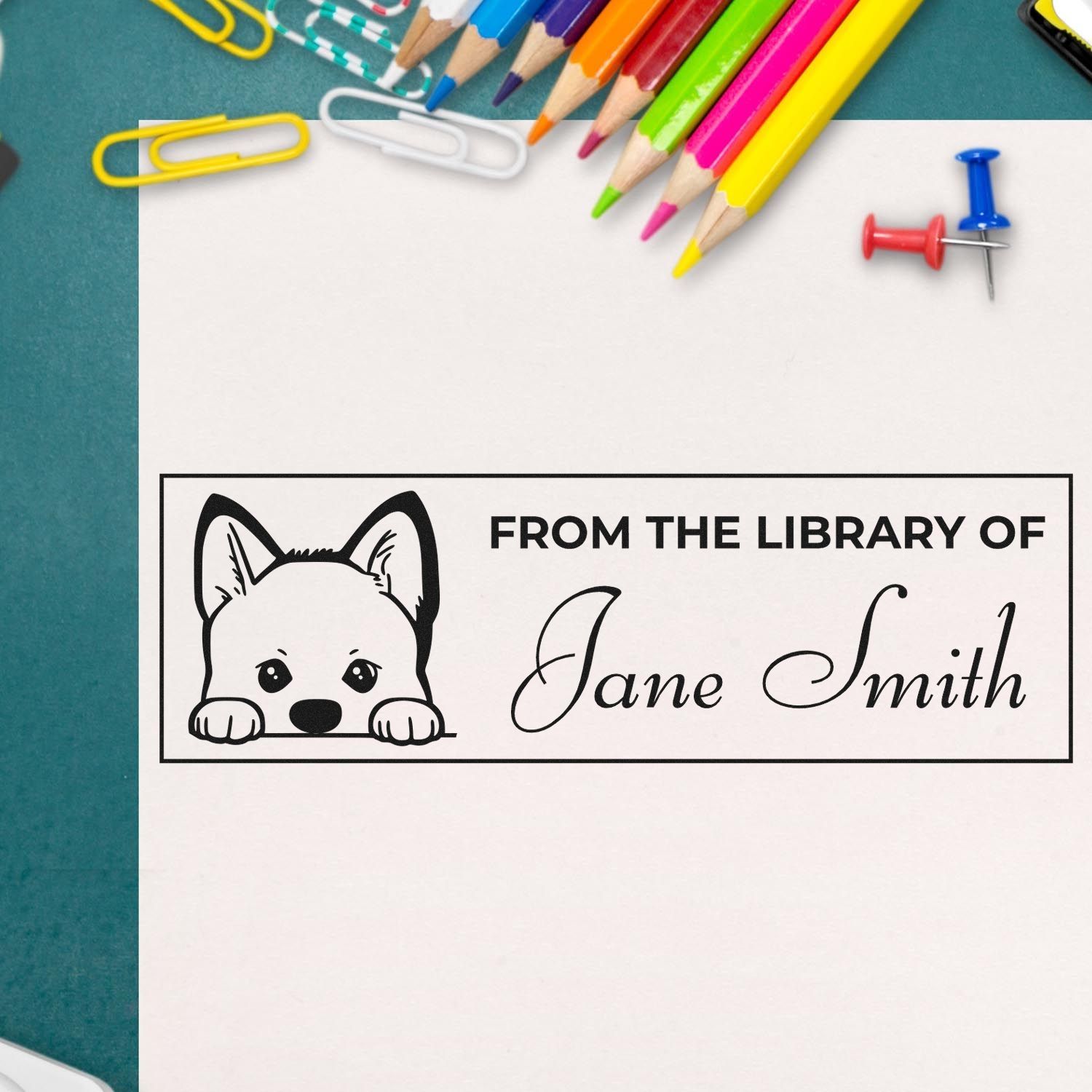 Custom library stamp and seal with black puppy design, Jane Smith text, on white paper with colorful pencils and push pins.