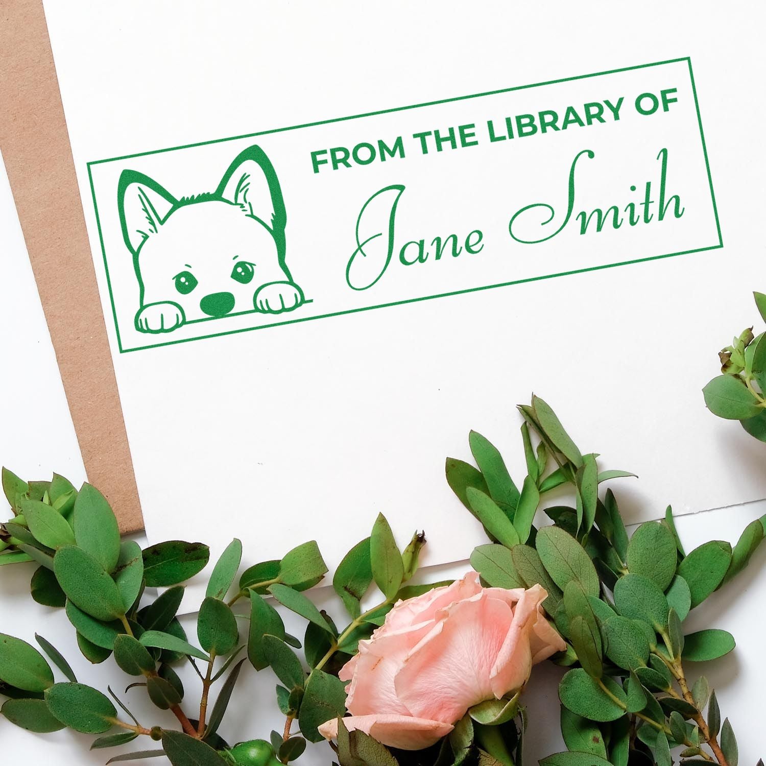 Green custom library stamp with puppy icon and Jane Smith text on white paper, framed by greenery and a pink rose.