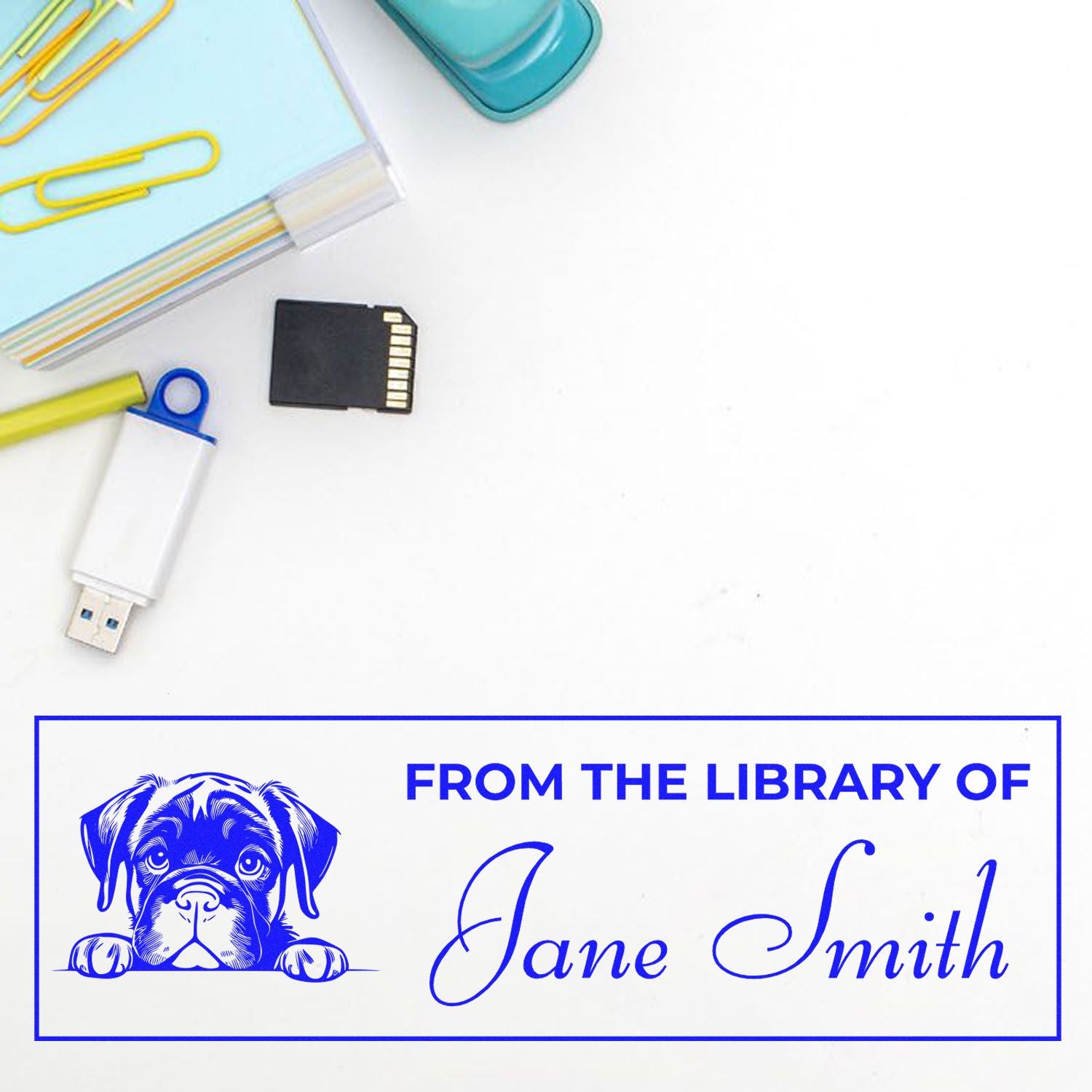Blue custom library stamp seal with dog illustration and Jane Smith text, beside USB drive, SD card, and paperclips.