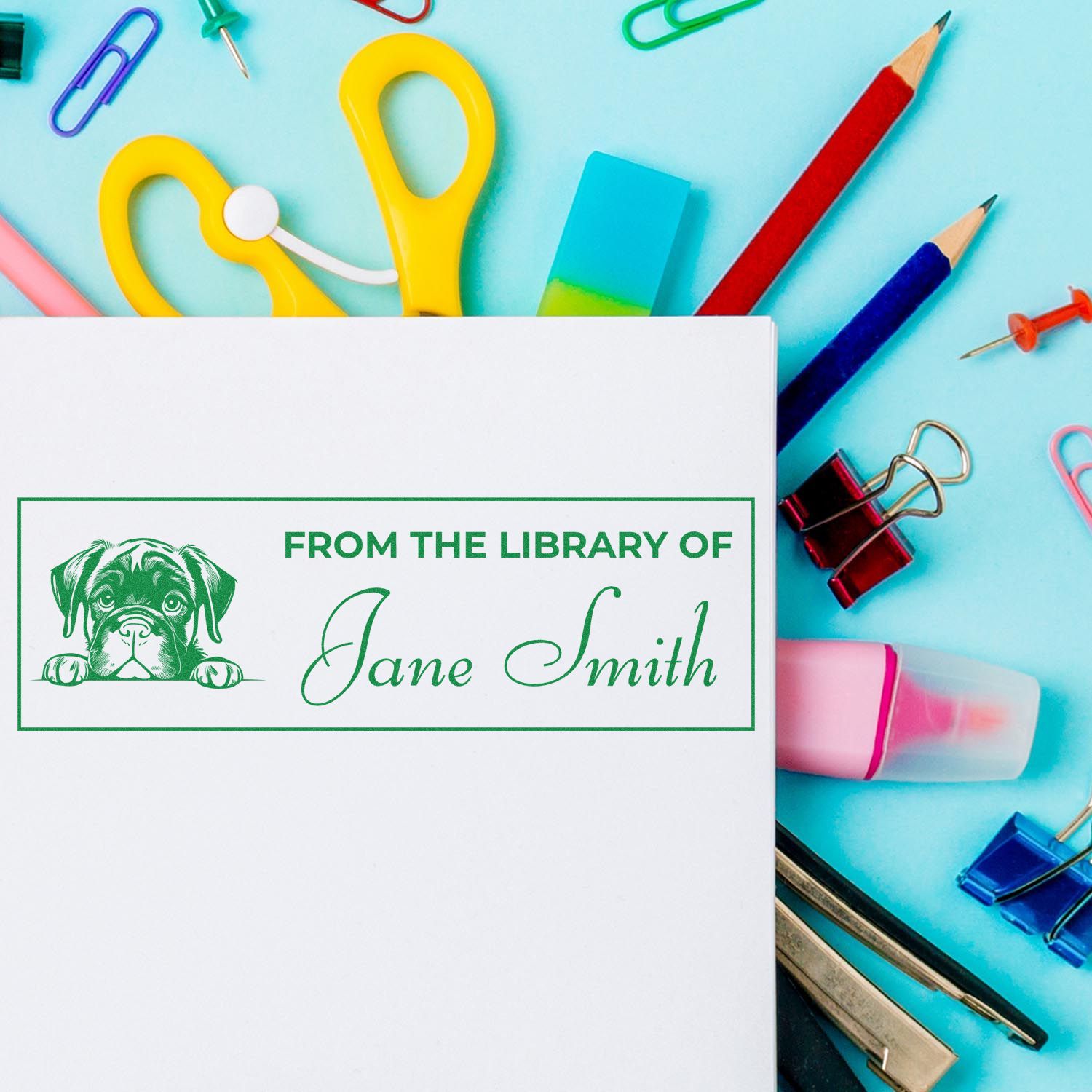 Green custom library stamp with dog and Jane Smith on white paper, surrounded by colorful school seal tools on a blue background.
