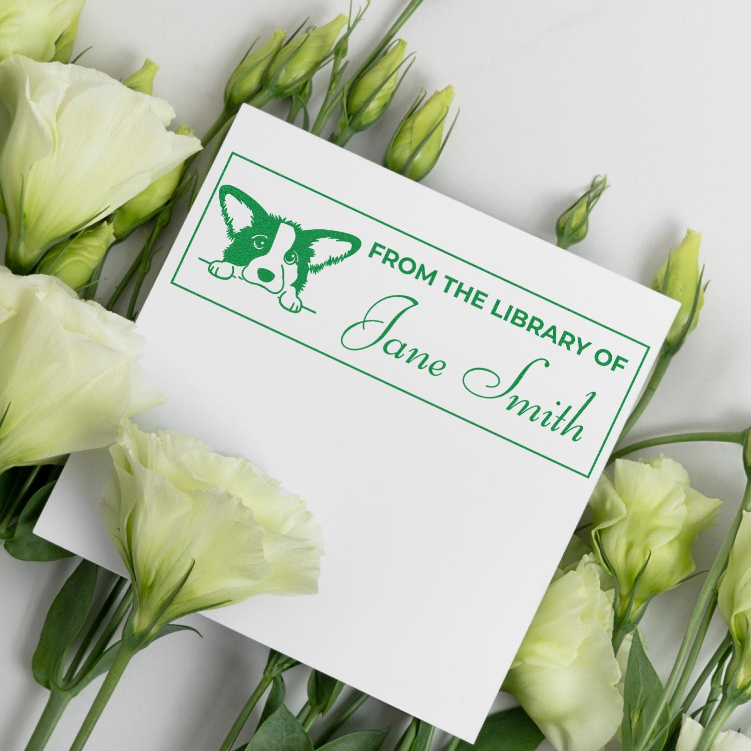 Green custom library stamp and seal with dog logo and Jane Smith name on white card, surrounded by pale yellow flowers.