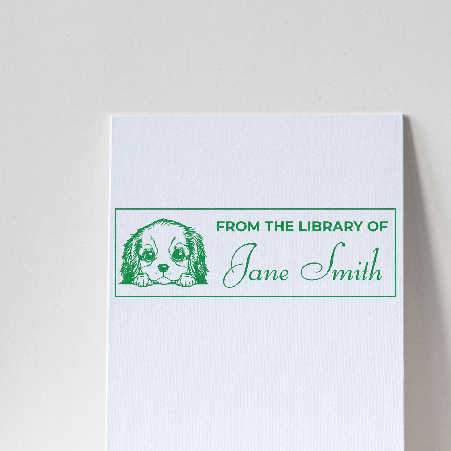 Green custom library stamp and seal with dog illustration, reading From the Library of Jane Smith, on white textured paper.