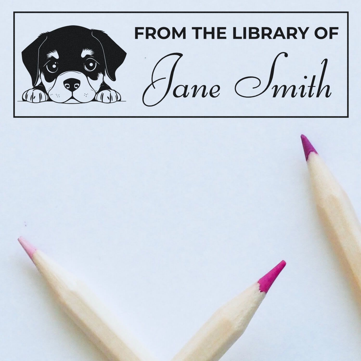 Black-and-white dog library stamp seal reading From the Library of Jane Smith on white paper with pink pencil tips.