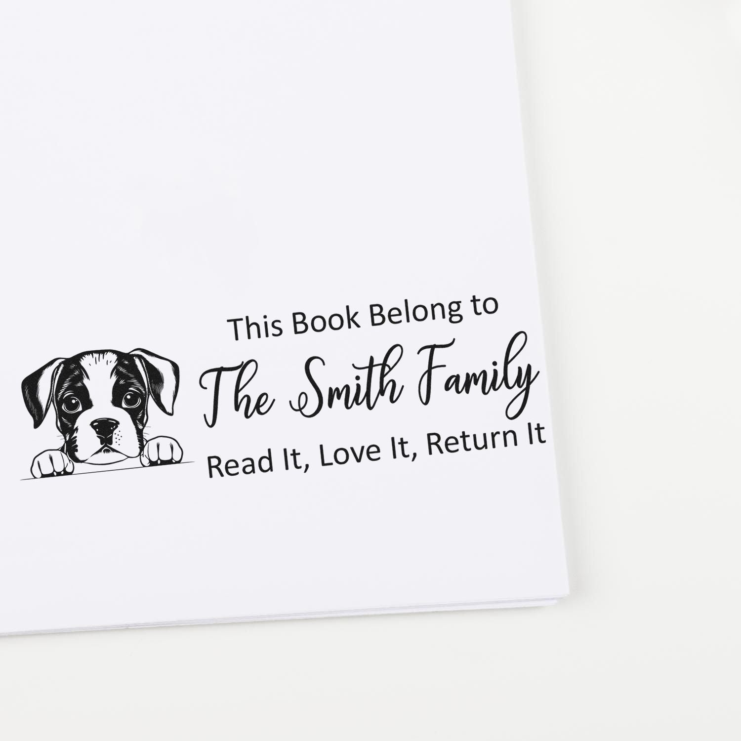 Black custom book stamp with puppy seal and text, This Book Belong to The Smith Family, Read It, Love It, Return It, on white page.