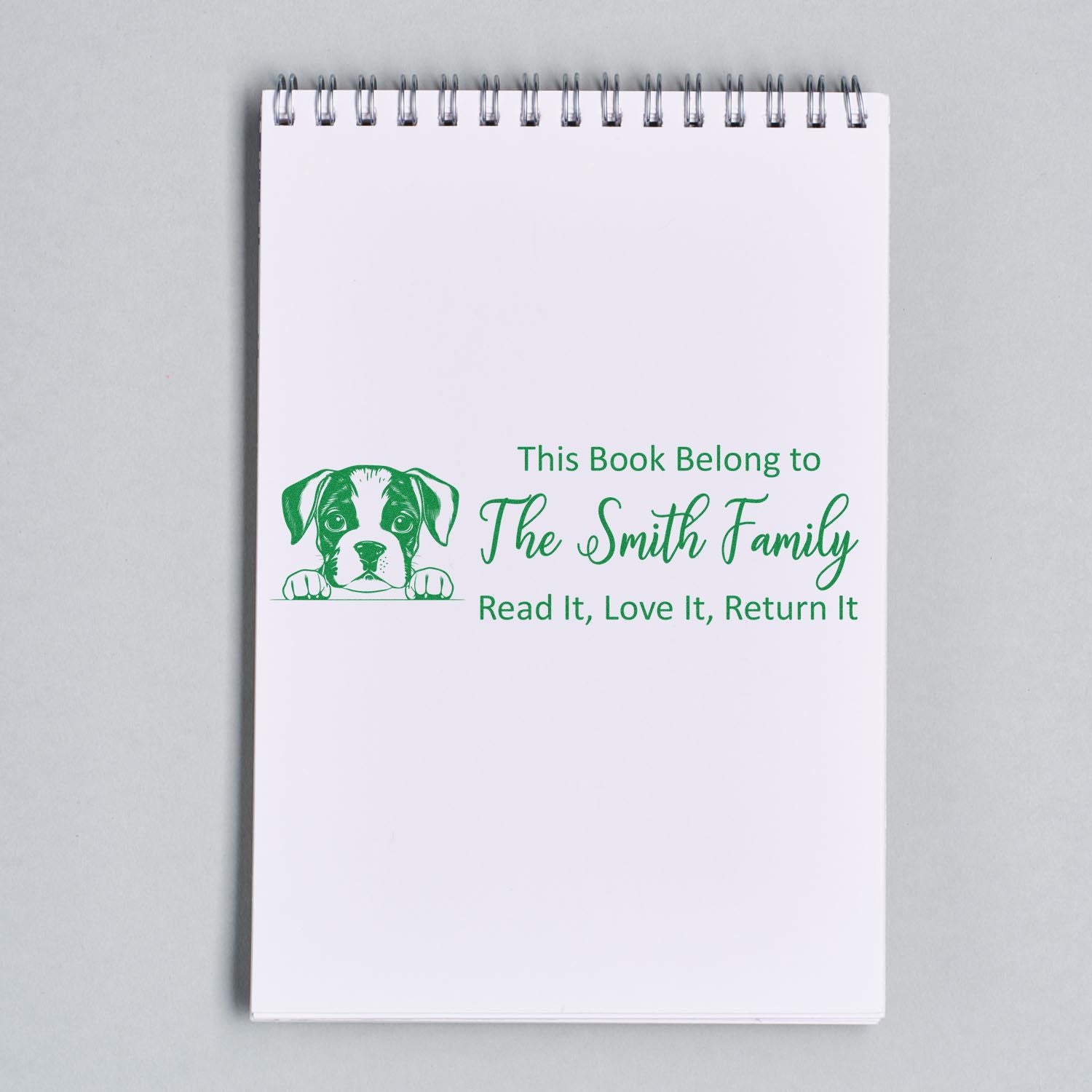 White spiral notebook with green custom book ownership stamp, dog seal graphic, and text: The Smith Family, Read It, Love It, Return It.
