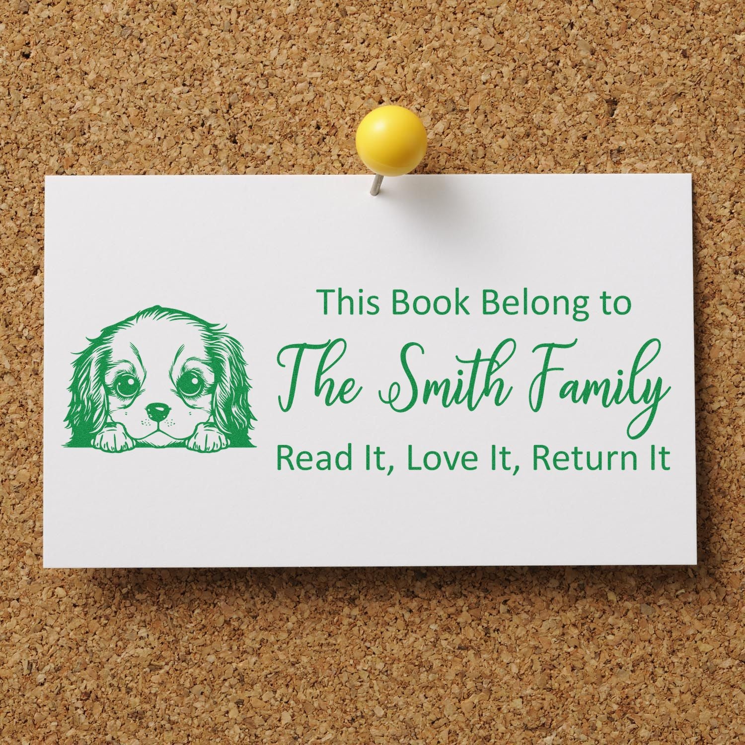 Green custom book stamp seal with dog graphic and The Smith Family text on a white card pinned to corkboard.