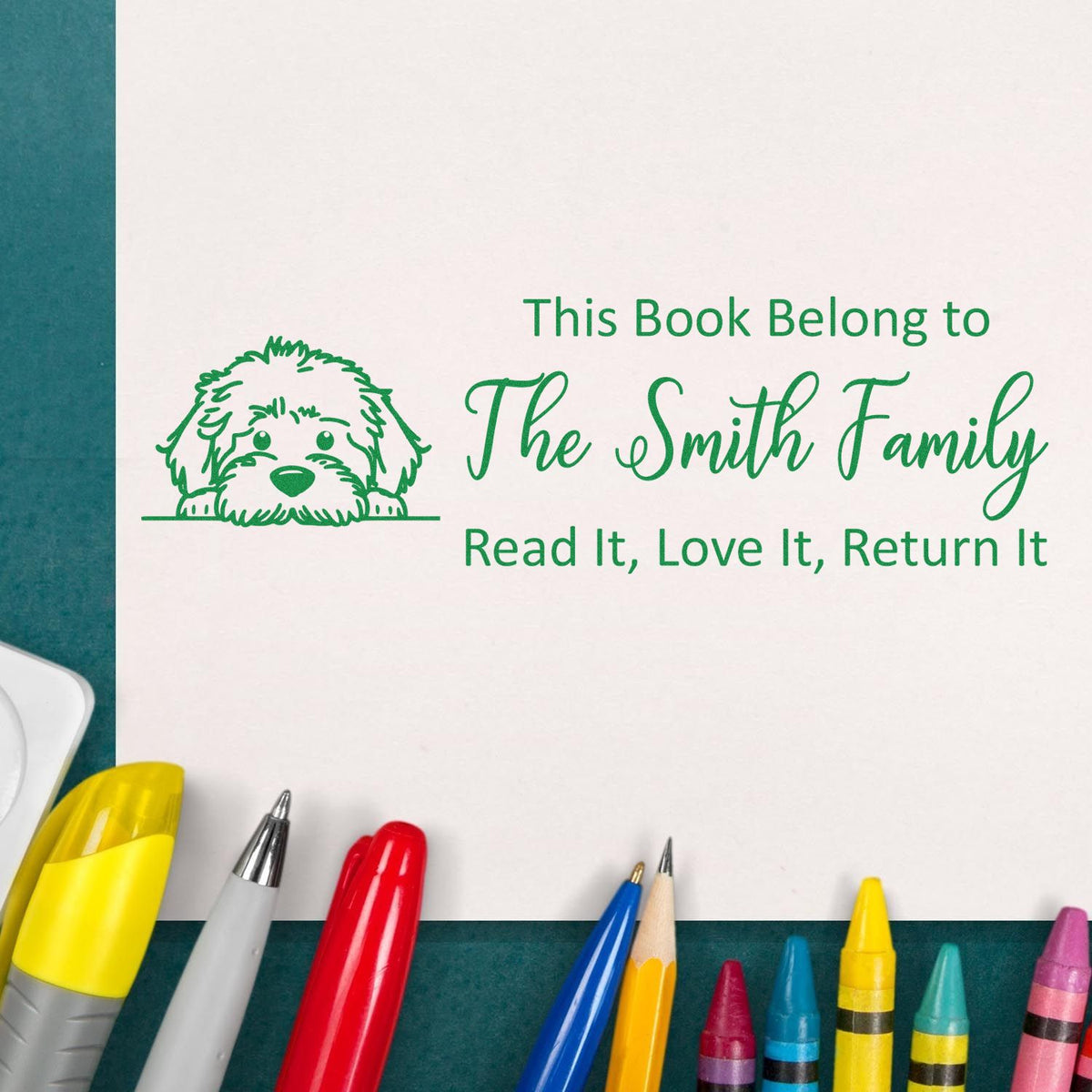 Green custom book stamp and seal with dog icon, The Smith Family text, on white paper with colorful pens.