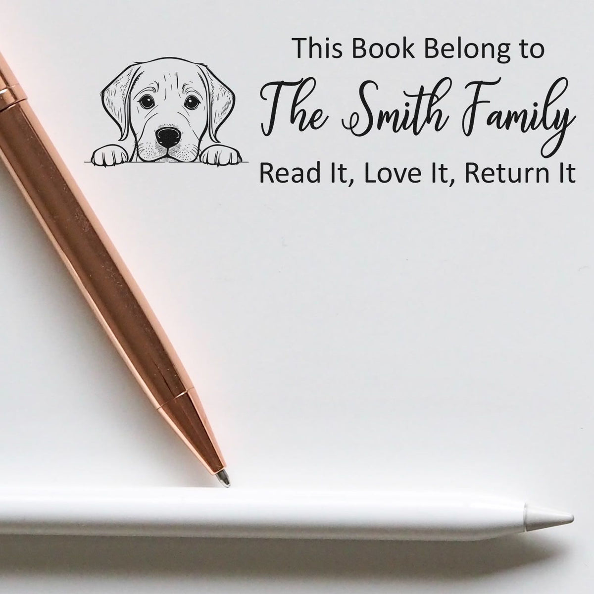 Custom self-inking book stamp and seal with black puppy artwork, Smith Family text, and rose-gold pen on white.