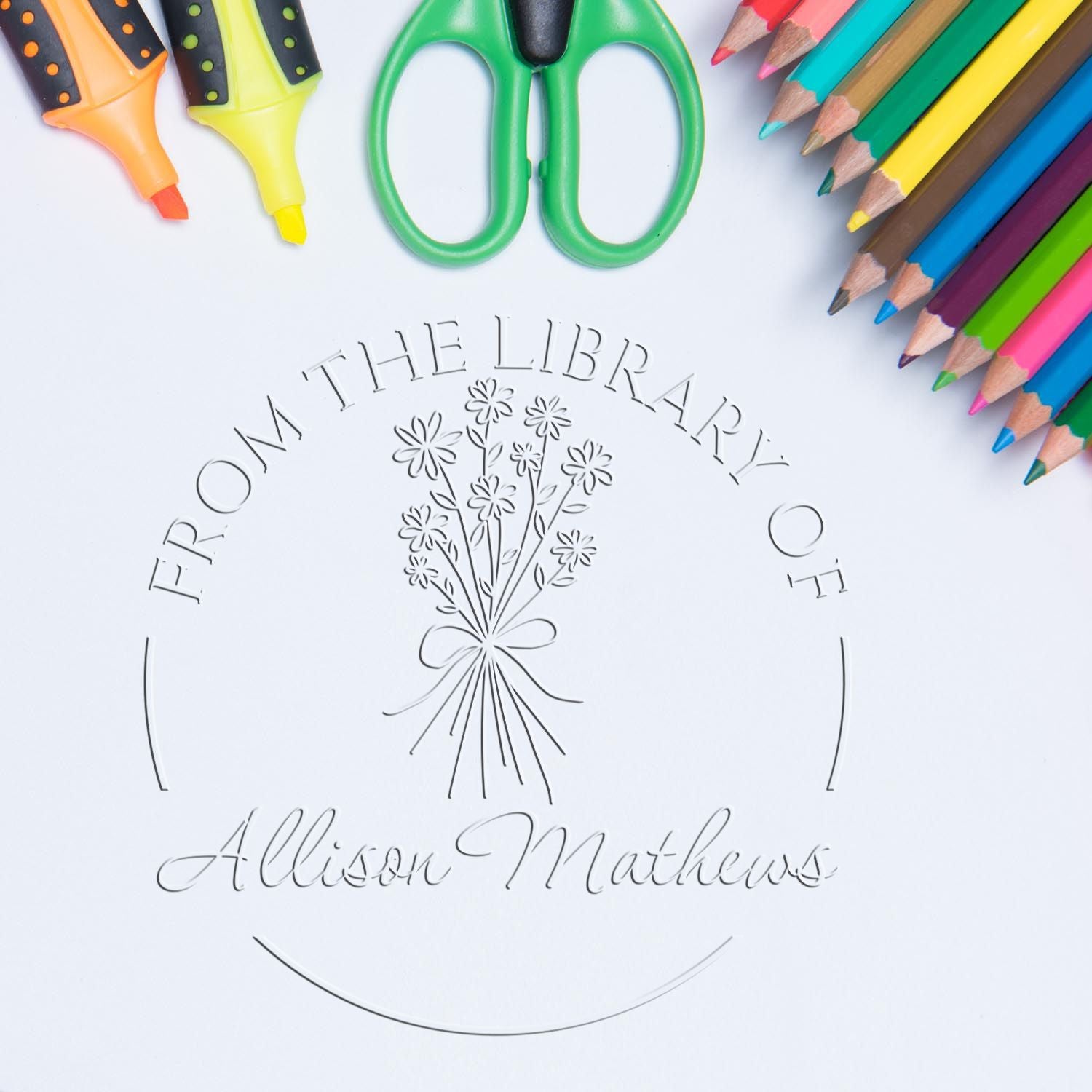 Embossed library seal with floral logo, framed by colorful pencils, green scissors, and orange-yellow stamp tools.