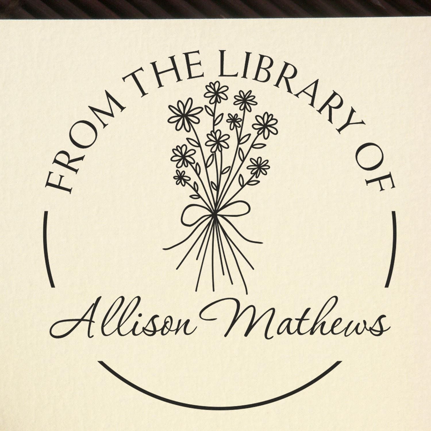 Black custom library stamp seal with floral bouquet and Allison Mathews on a cream background.