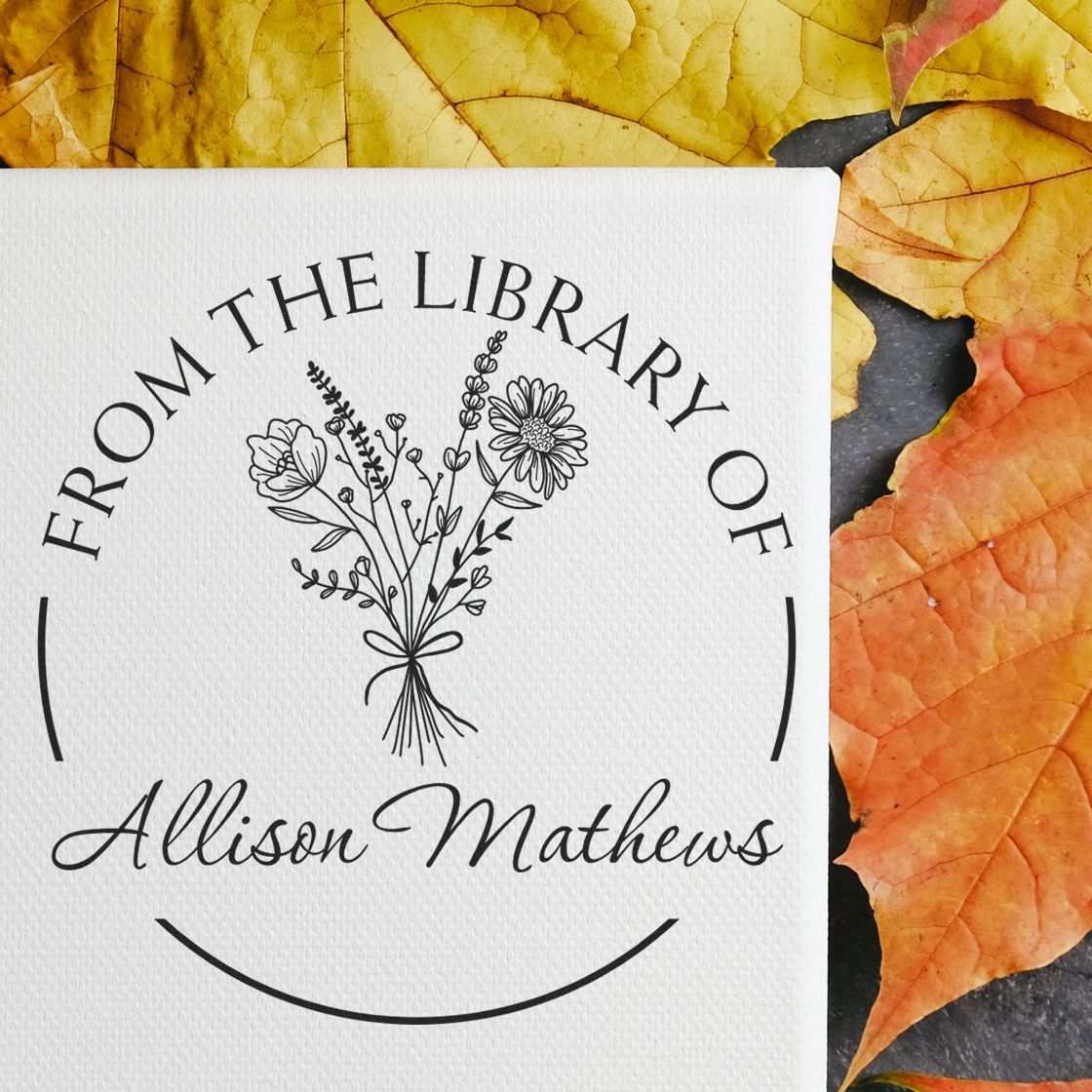 Custom black floral library stamp and seal for Allison Mathews on white card, framed by yellow-orange autumn leaves.