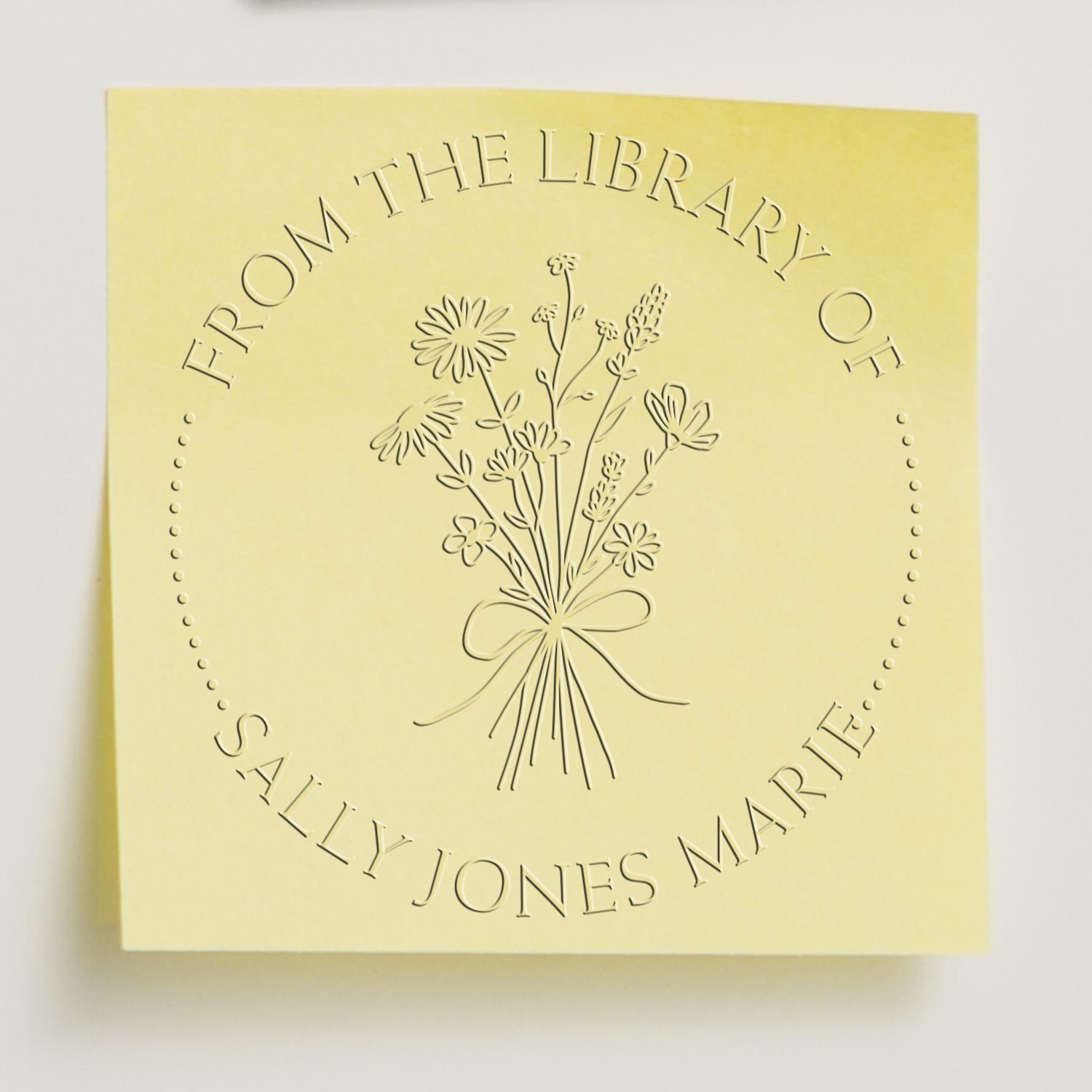 Pale yellow embossed library seal stamp with floral bouquet and circular text for Sally Jones Marier