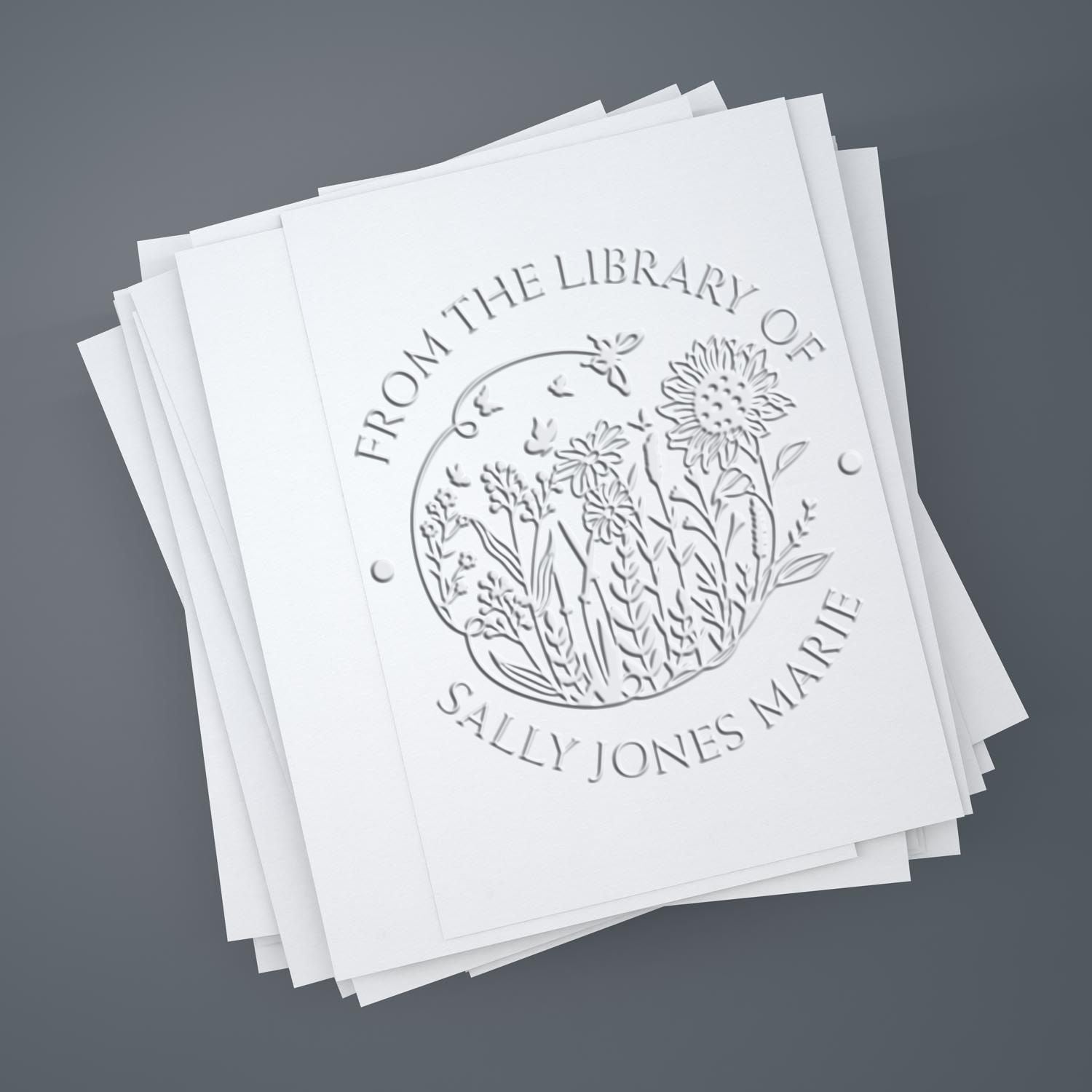 Embossed white stamp seal stack with floral botanical design and Sally Jones Marie text on a gray background.