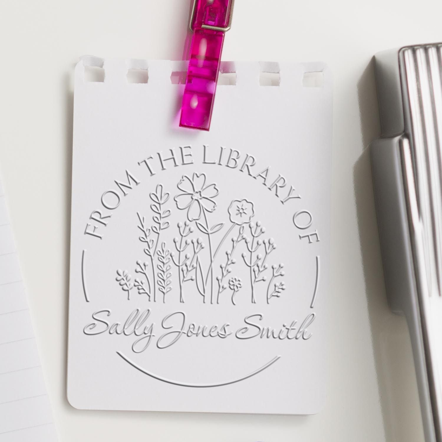 White personalized library stamp seal card for Sally Jones Smith, with floral embossing, pink clip, and silver binder edge.
