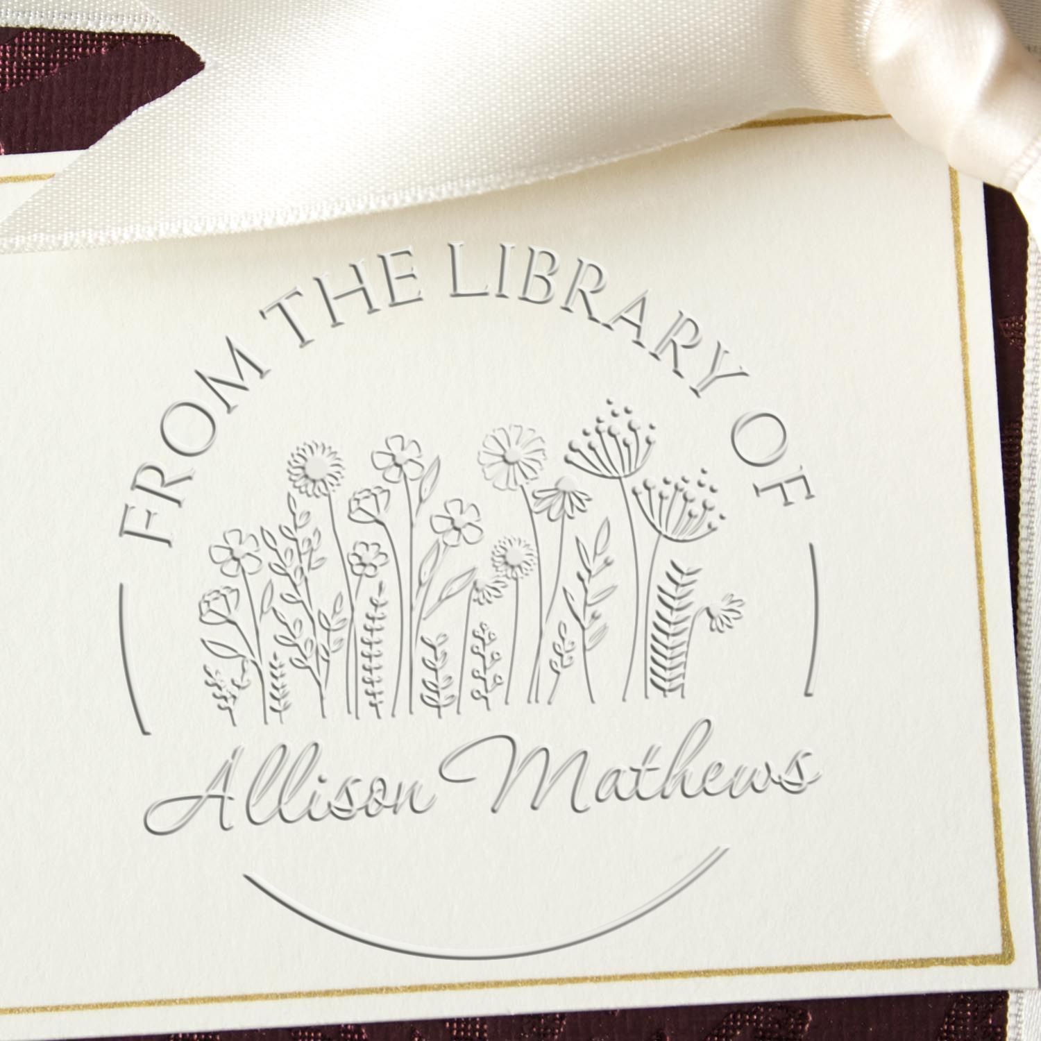 Embossed silver library stamp seal on cream card, with floral line art, white ribbon, gold border, and Allison Mathews name.