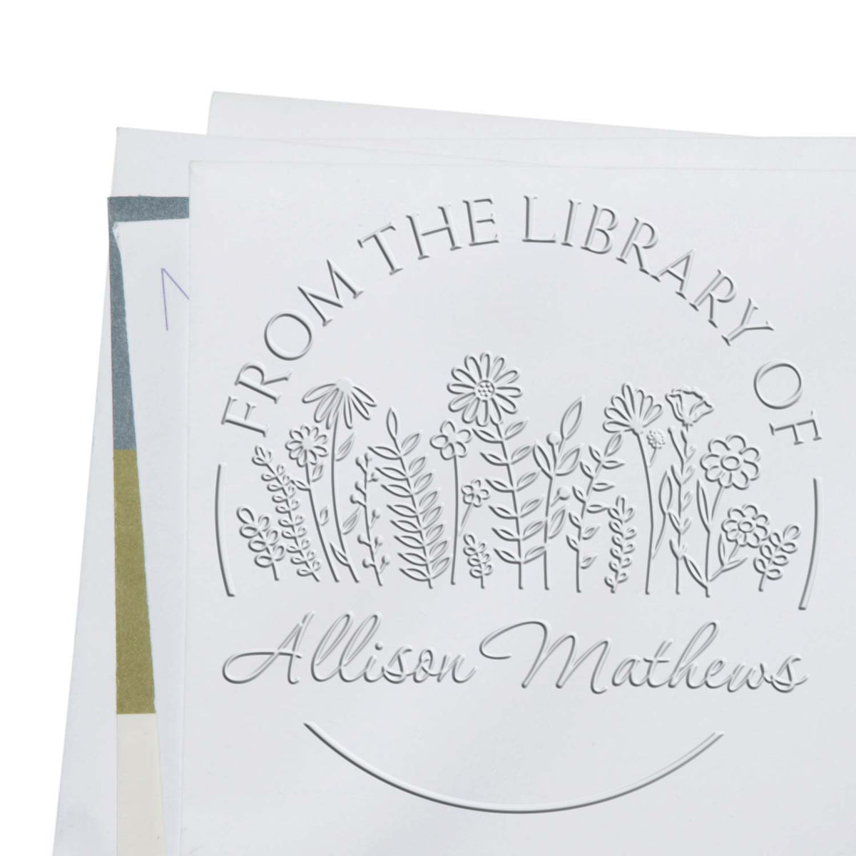 Shiny floral stamp in use featuring a custom book lover embossing seal with elegant flower designs.