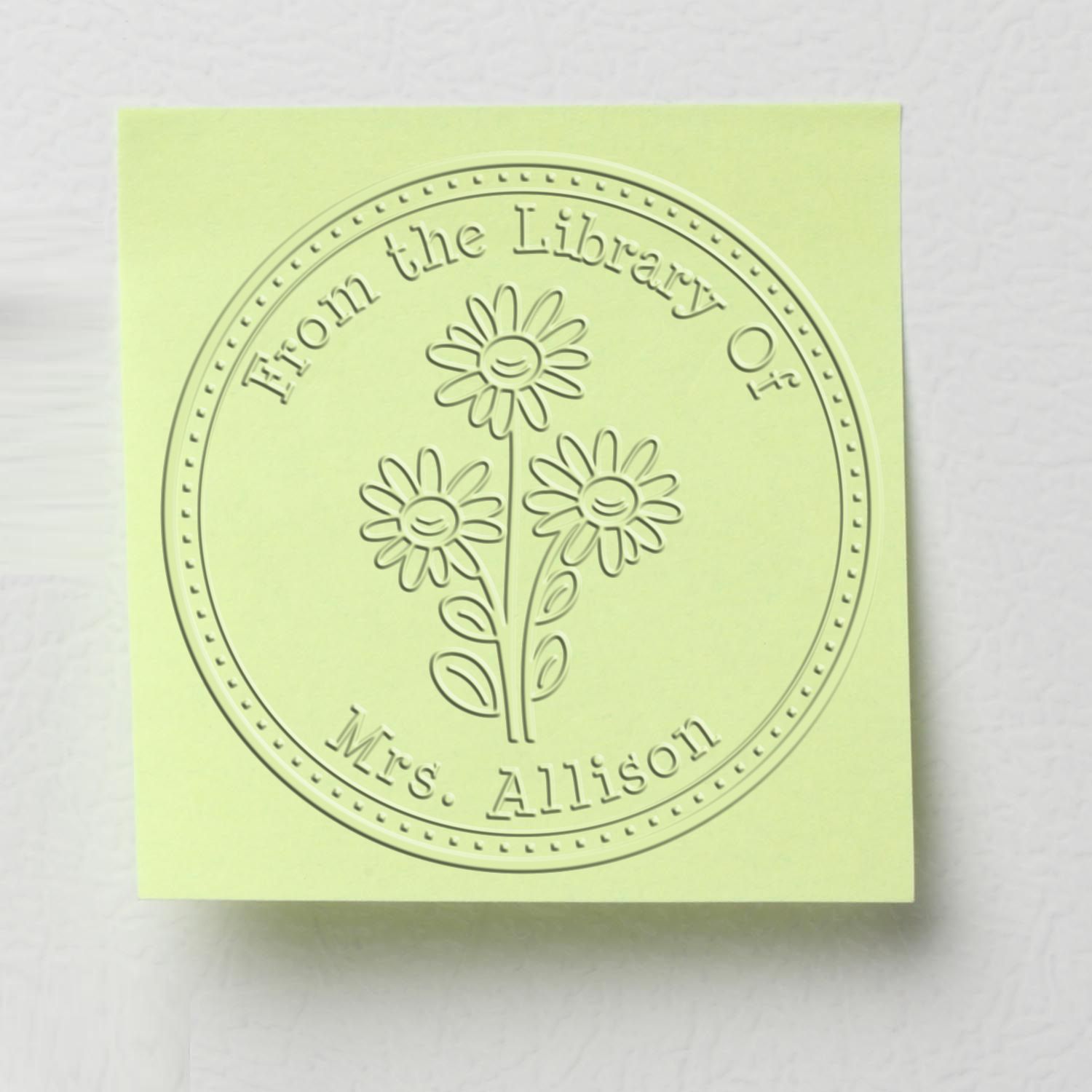 Pale green embossed library stamp seal with three flowers and dotted circular border reading From the Library of Mrs. Allison