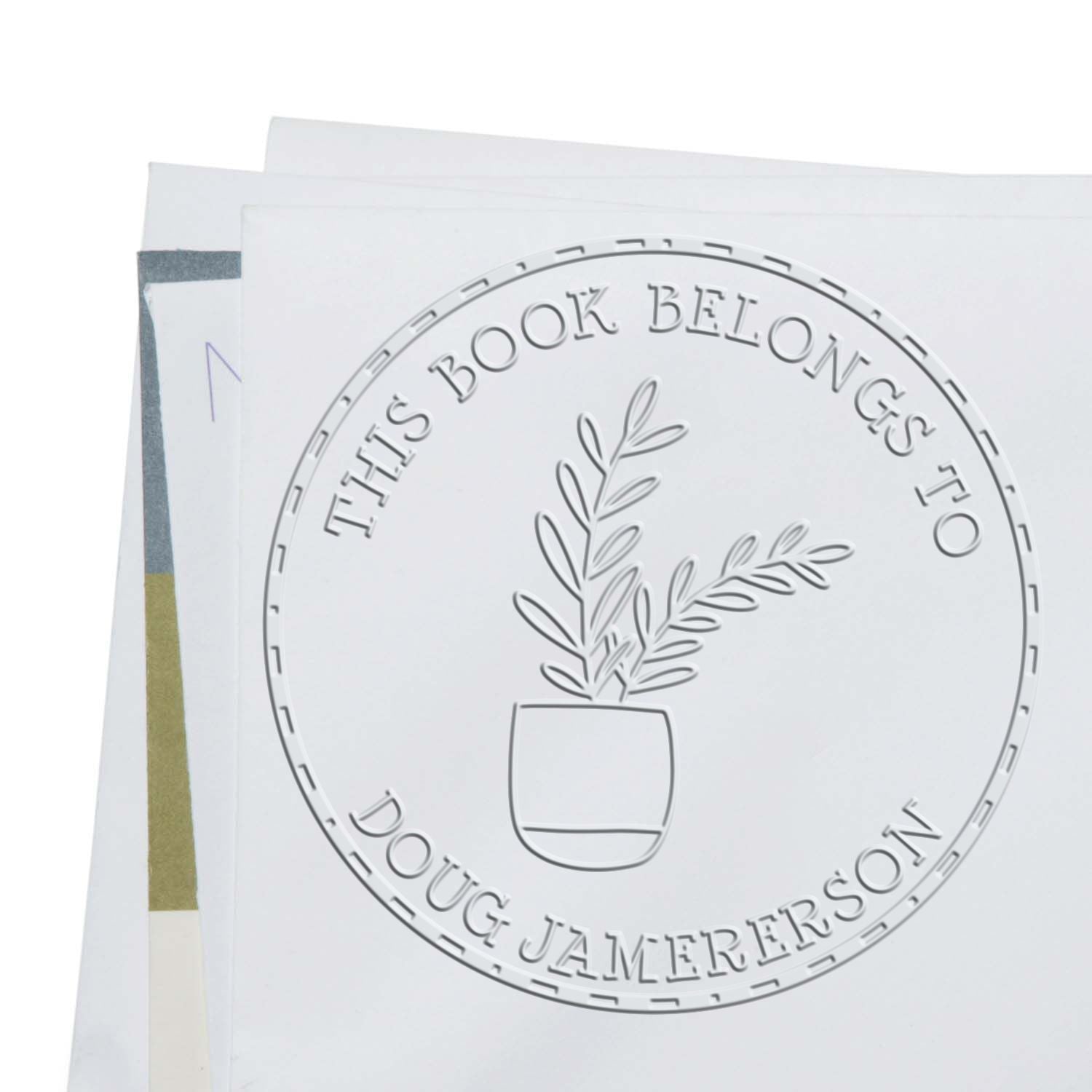 White embossed stamp seal with potted plant on stacked papers, reading This Book Belongs to Doug Jamerson.