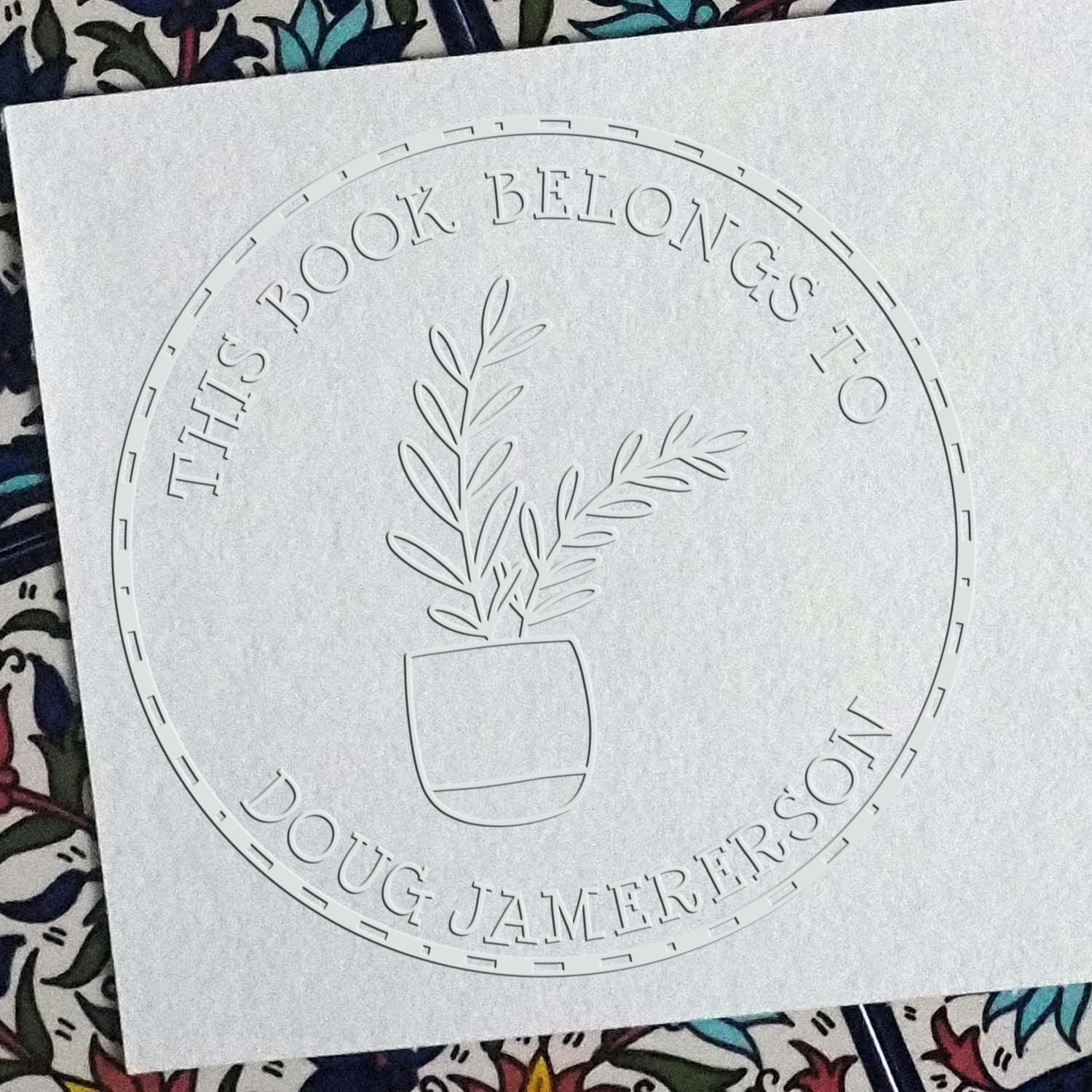 White embossed circular book stamp seal with potted plant and This book belongs to Doug Jamerson text.