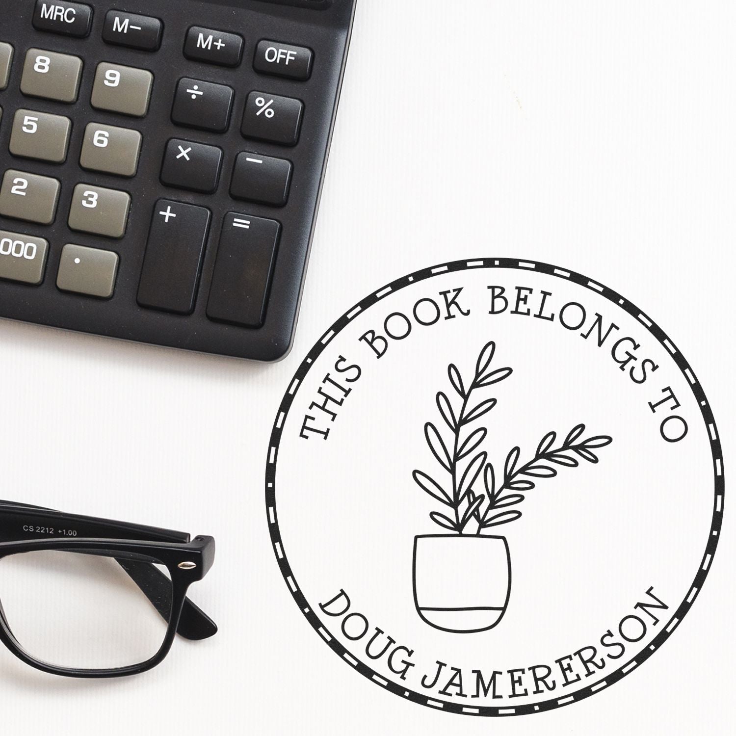 Black round stamp seal with potted plant and This Book Belongs to Doug Jamerson, beside a calculator and black eyeglasses.