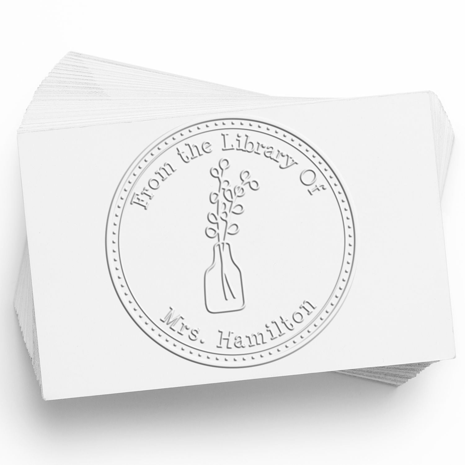 White embossed library stamp seal on stacked cards, with vase design and text From the Library of Mrs. Hamilton