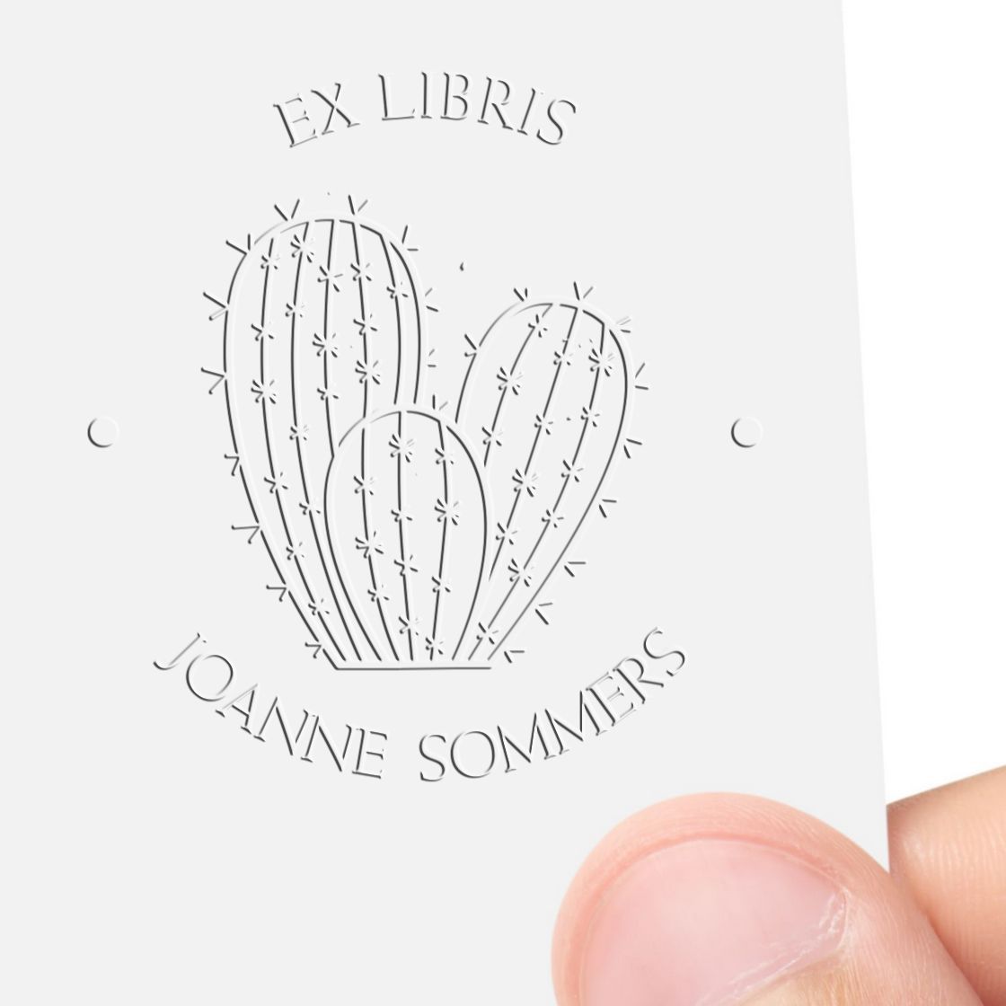 White embossed ex libris stamp seal with cactus design and Joanne Sommers text on a white card.