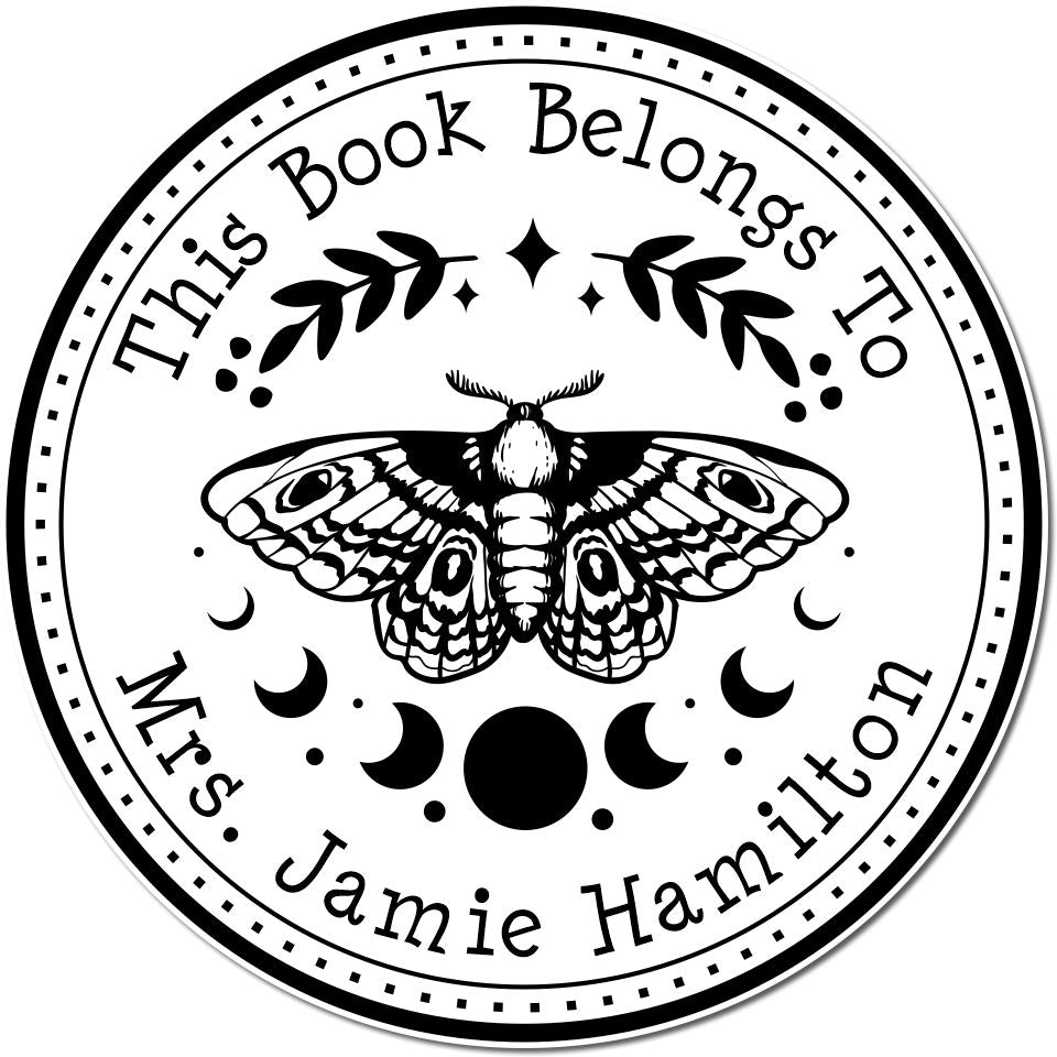 Black-and-white circular custom stamp seal with a moth, moon phases, and This Book Belongs To Mrs. Jamie Hamilton text.