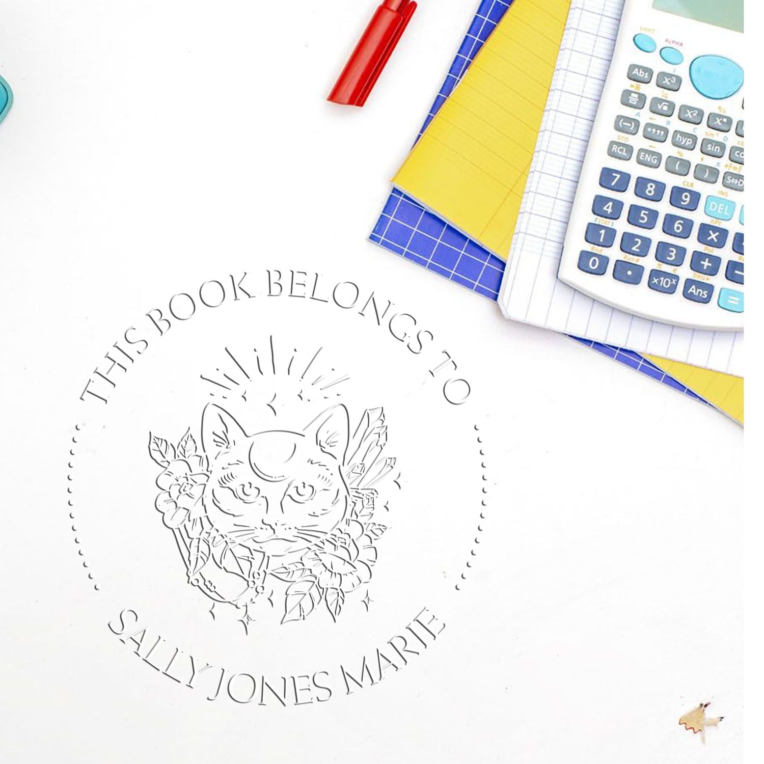 Custom circular book-belongings stamp seal with cat illustration, surrounded by notebooks, calculator, and red pen.