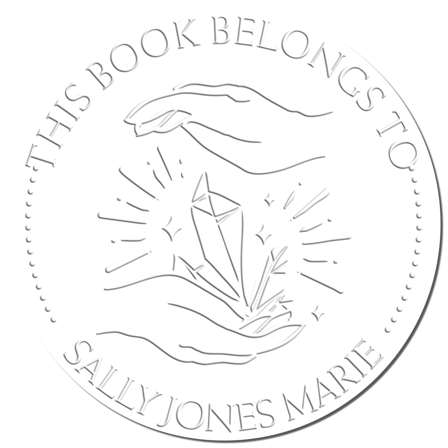 Silver embossed circular stamp and seal with hands holding crystal, reading This Book Belongs to Sally Jones Marie.