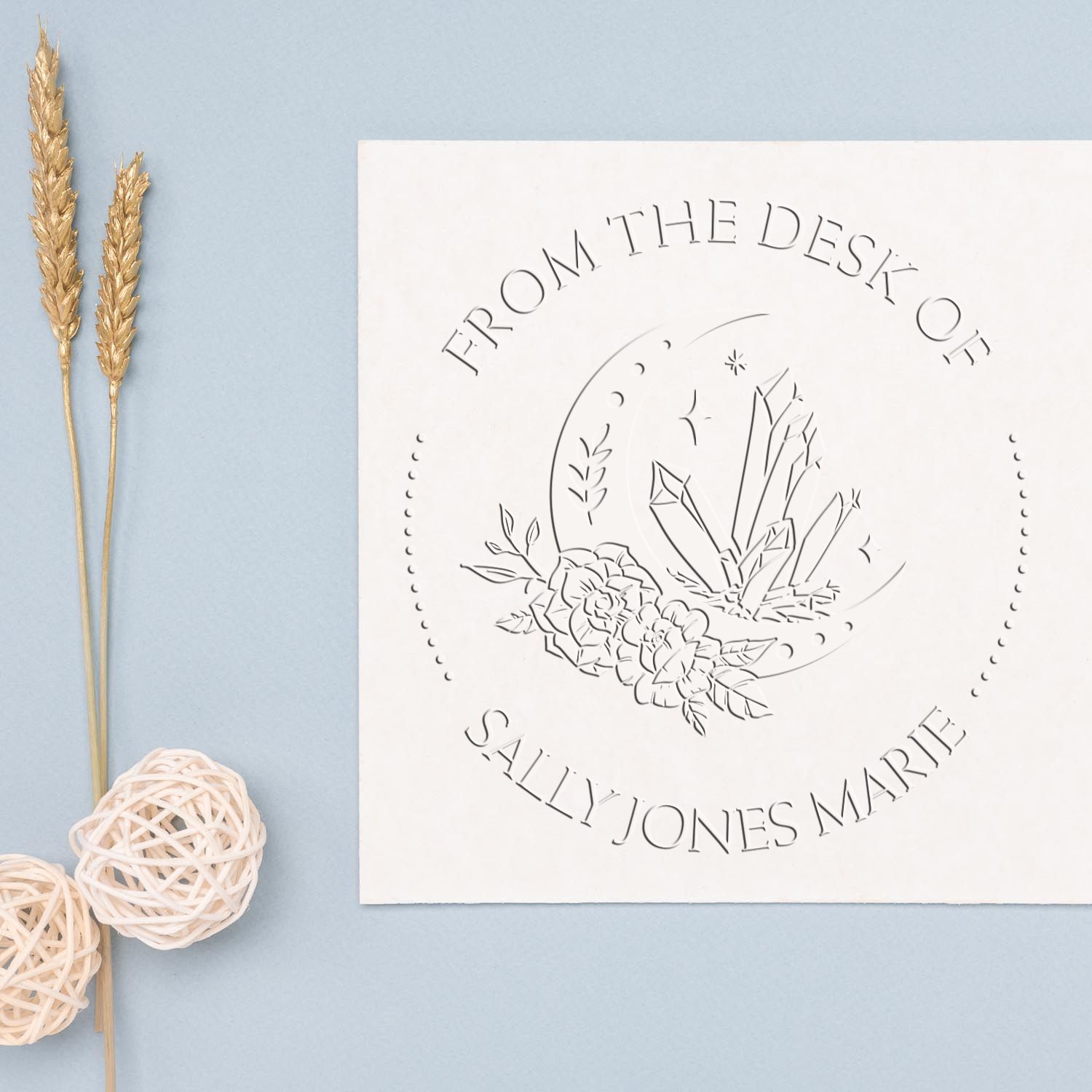Custom white stamp and seal with floral moon design and From the Desk of Sally Jones Marie, on pale blue with gold wheat accents.