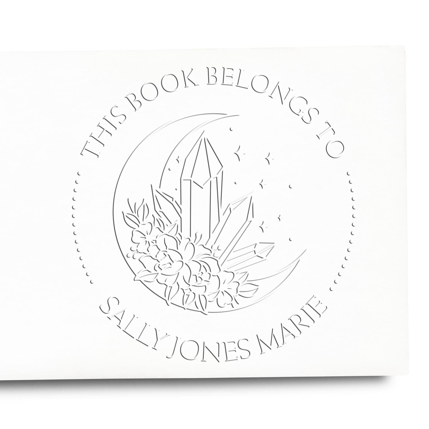 White embossed book stamp and seal with crescent moon, crystal, and flowers, reading This Book Belongs to Sally-Jones Marie.