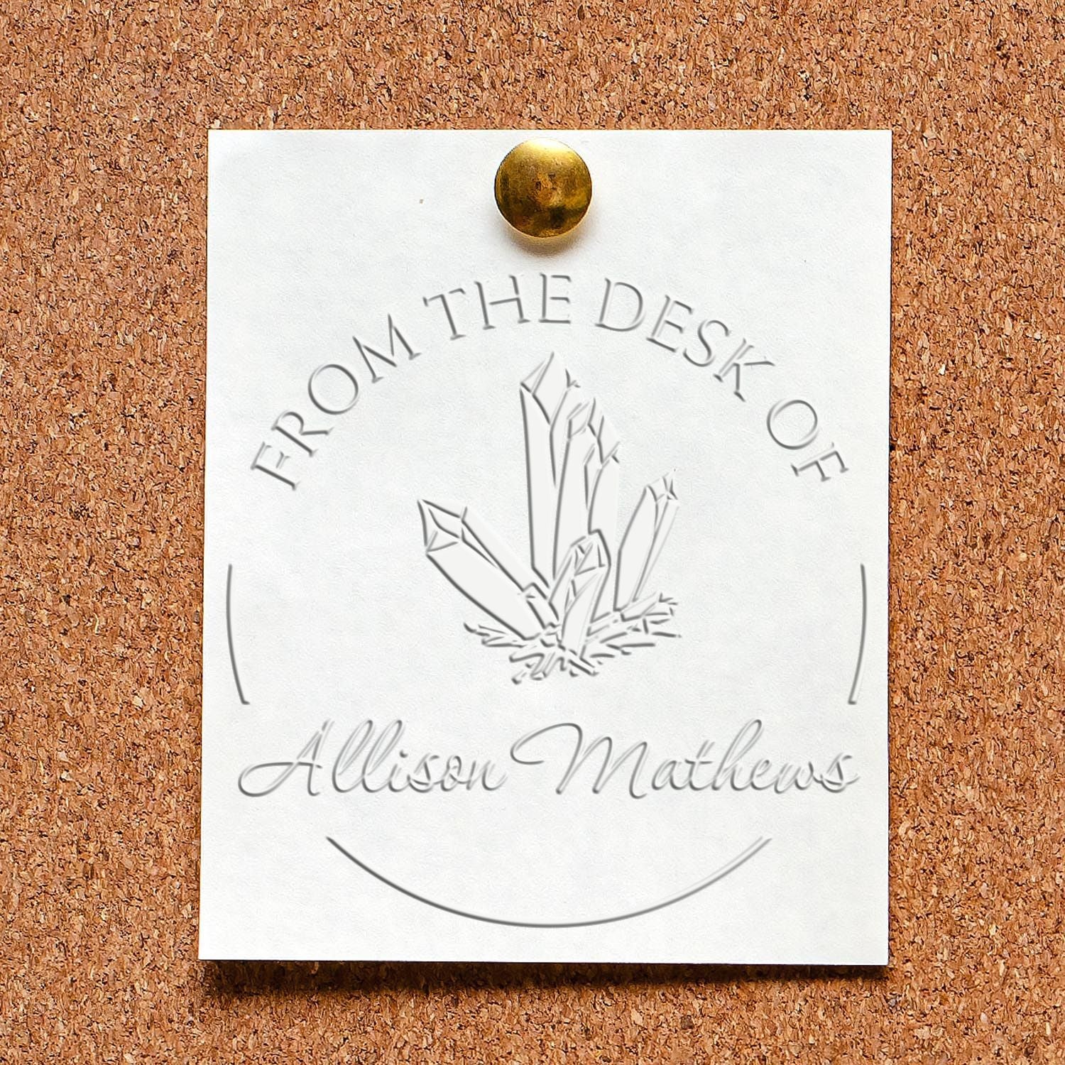 White embossed desk seal stamp card pinned with brass tack on corkboard, featuring crystal graphic and Allison Mathews text.