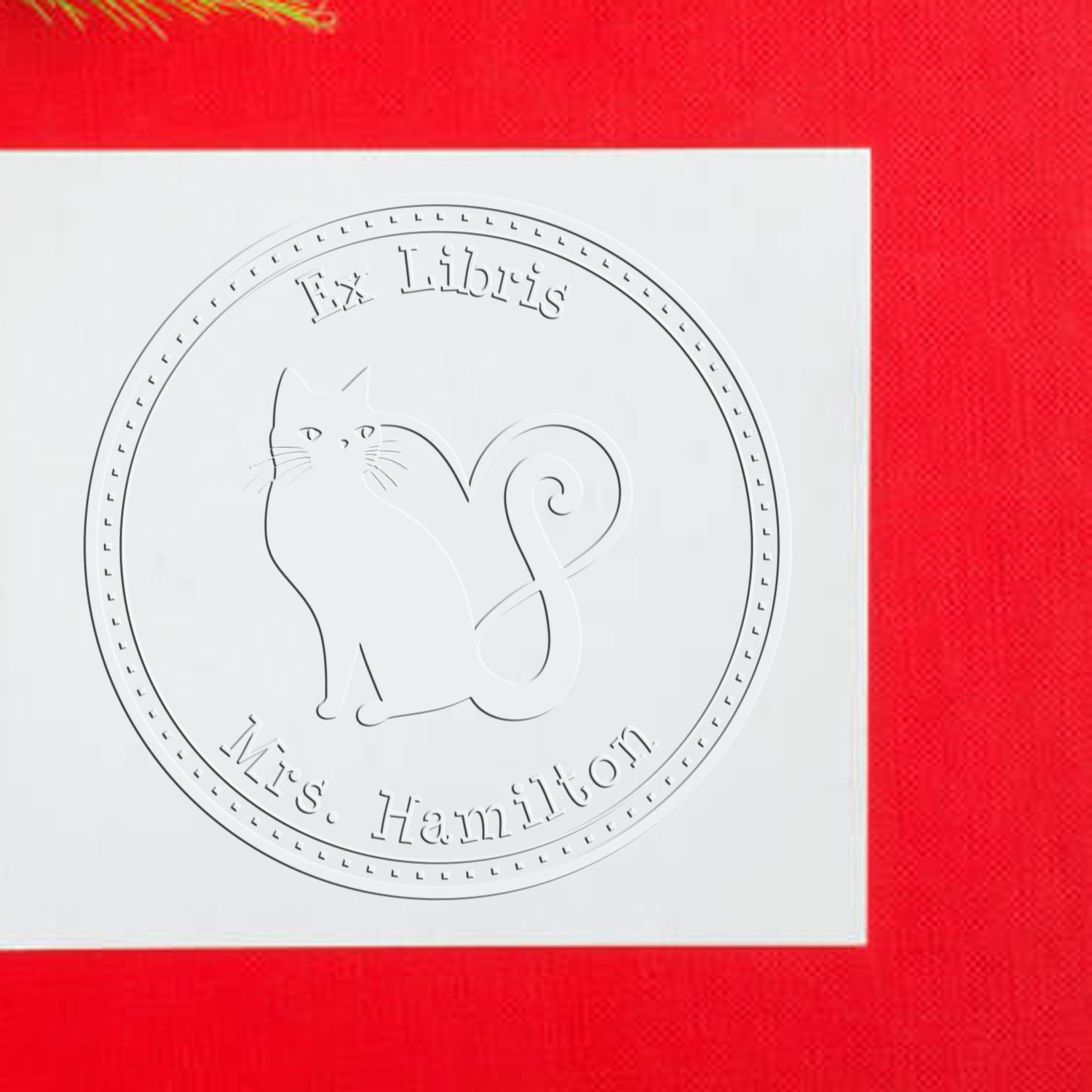 White embossed circular Ex Libris cat stamp seal on red background with Mrs. Hamilton text.