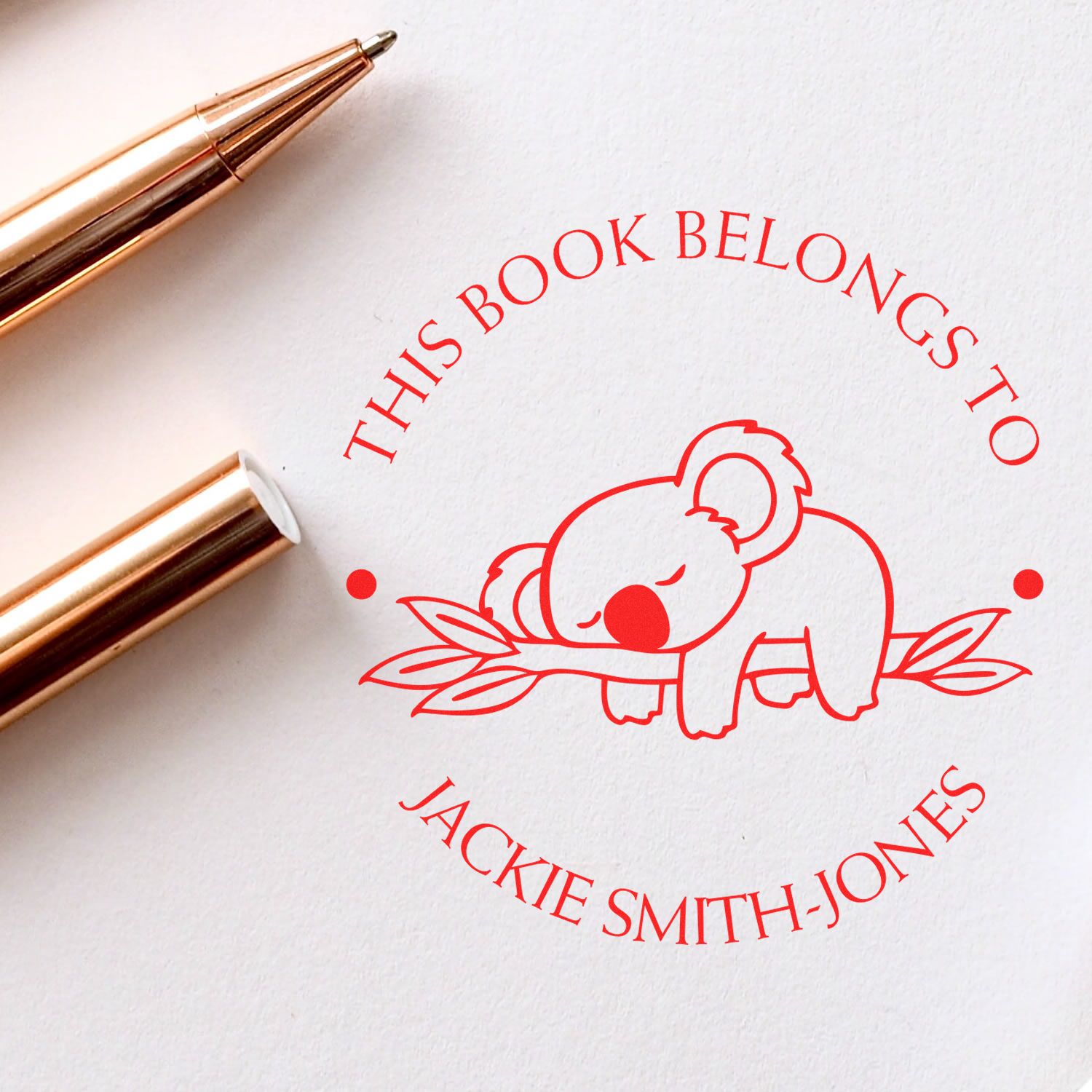 Red personalized book stamp seal with sleeping koala, This book belongs to Jackie Smith-Jones, beside gold stamp tools.