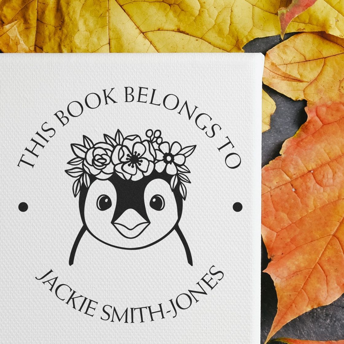 Personalized black book stamp and seal featuring a penguin with floral crown on white textured paper, framed by orange and yellow leaves.
