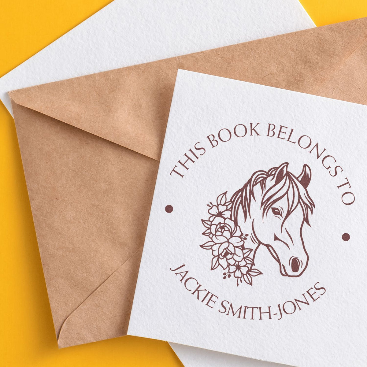 Custom brown stamp and seal on white card, with horse-and-floral logo over kraft envelopes on a bright yellow background.