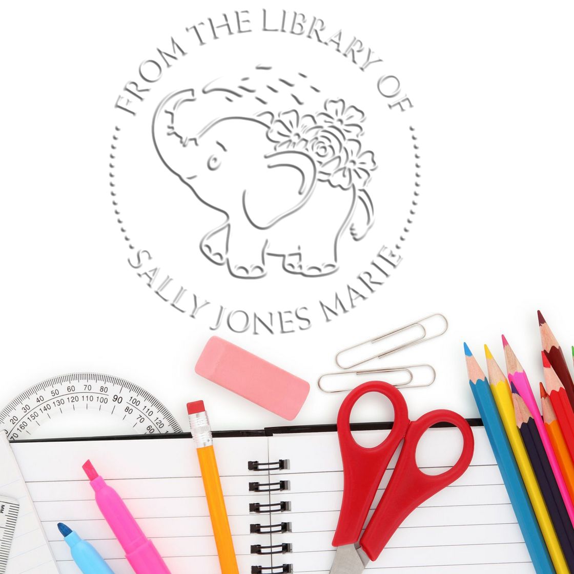 Custom gray round stamp seal with elephant and flowers, labeled Sally Jones Marie, on a white background with school supplies.